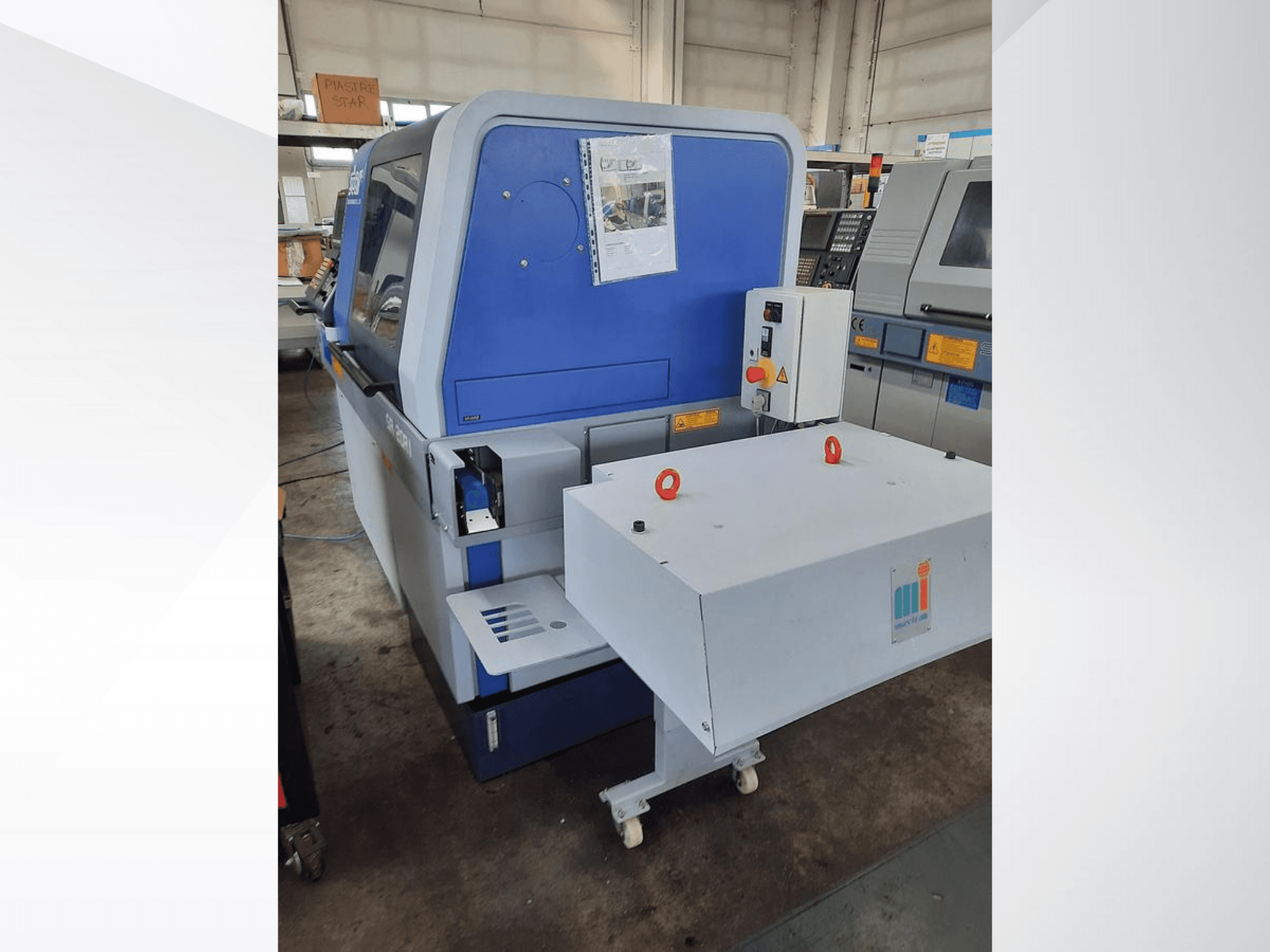 Синяя промышленная машина с белым конвейером, с панелью управления и прикрепленными элементами безопасности, вид сбоку.