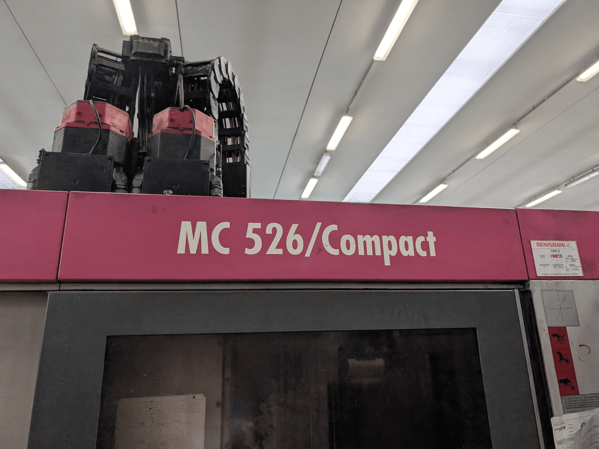 Розовый станок MC 526/Compact с двумя двигателями и кабелями, вид сверху. Наклейка Renishaw на боковой стороне.
