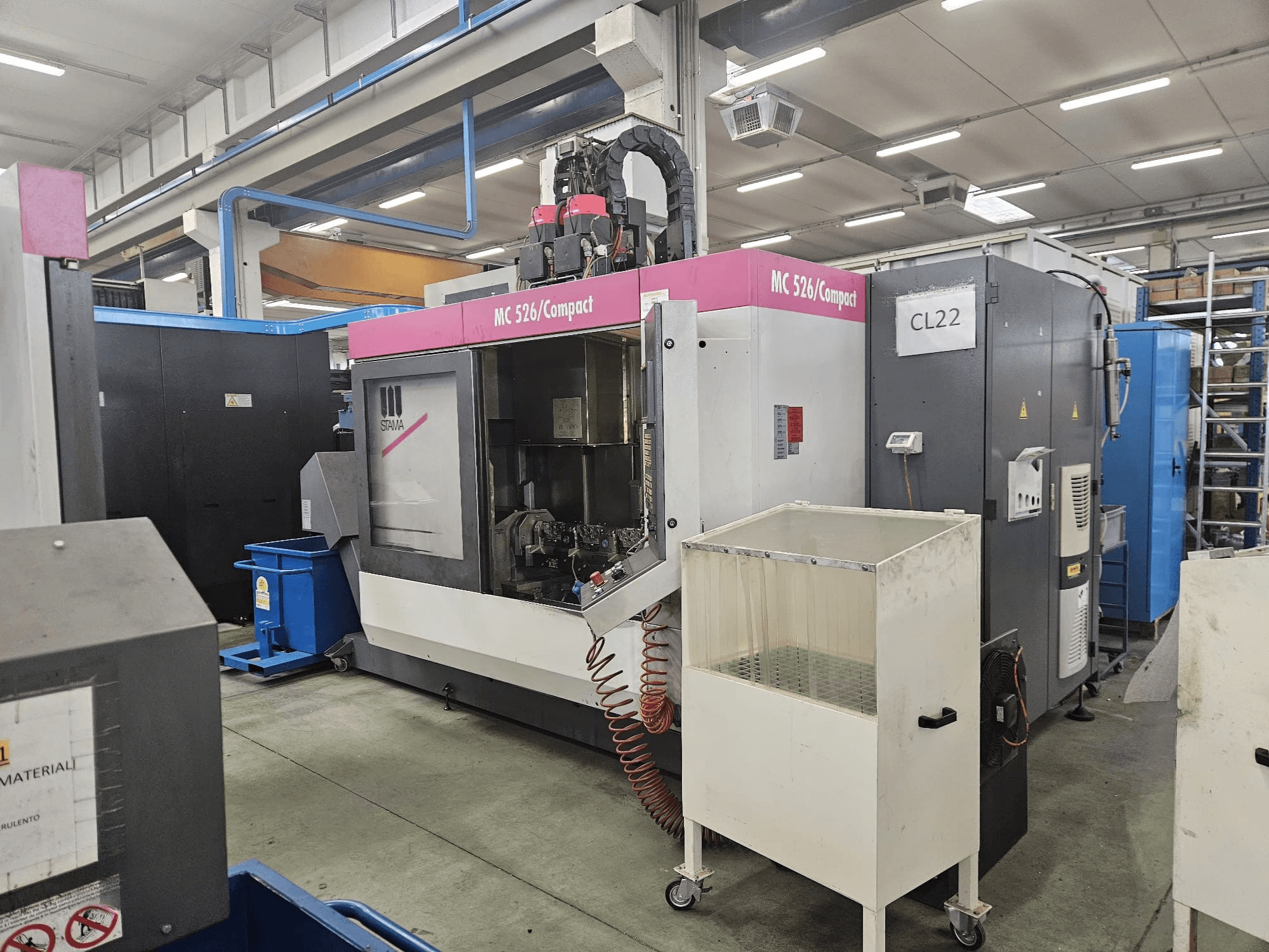 Компактный станок с ЧПУ MC 526 от Stama, вид сбоку, демонстрирующий панель управления, бак для охлаждающей жидкости и соседние механизмы.