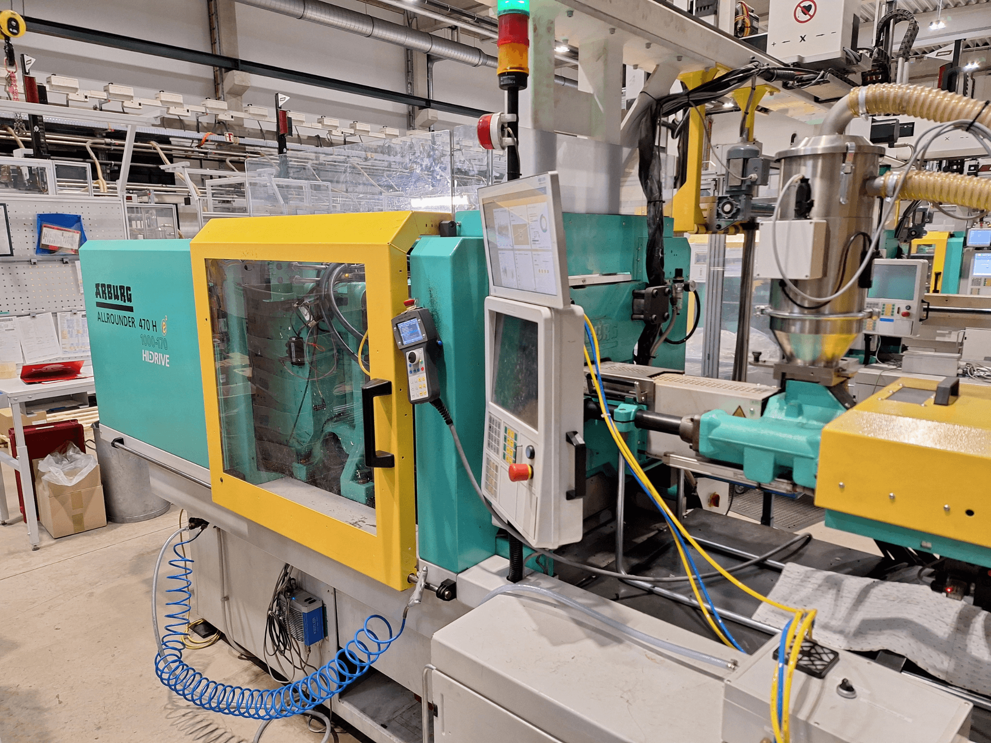 Гидравлическая машина для литья под давлением Arburg 470 H 1000-170, вид сбоку, демонстрирующий панель управления и систему подачи.