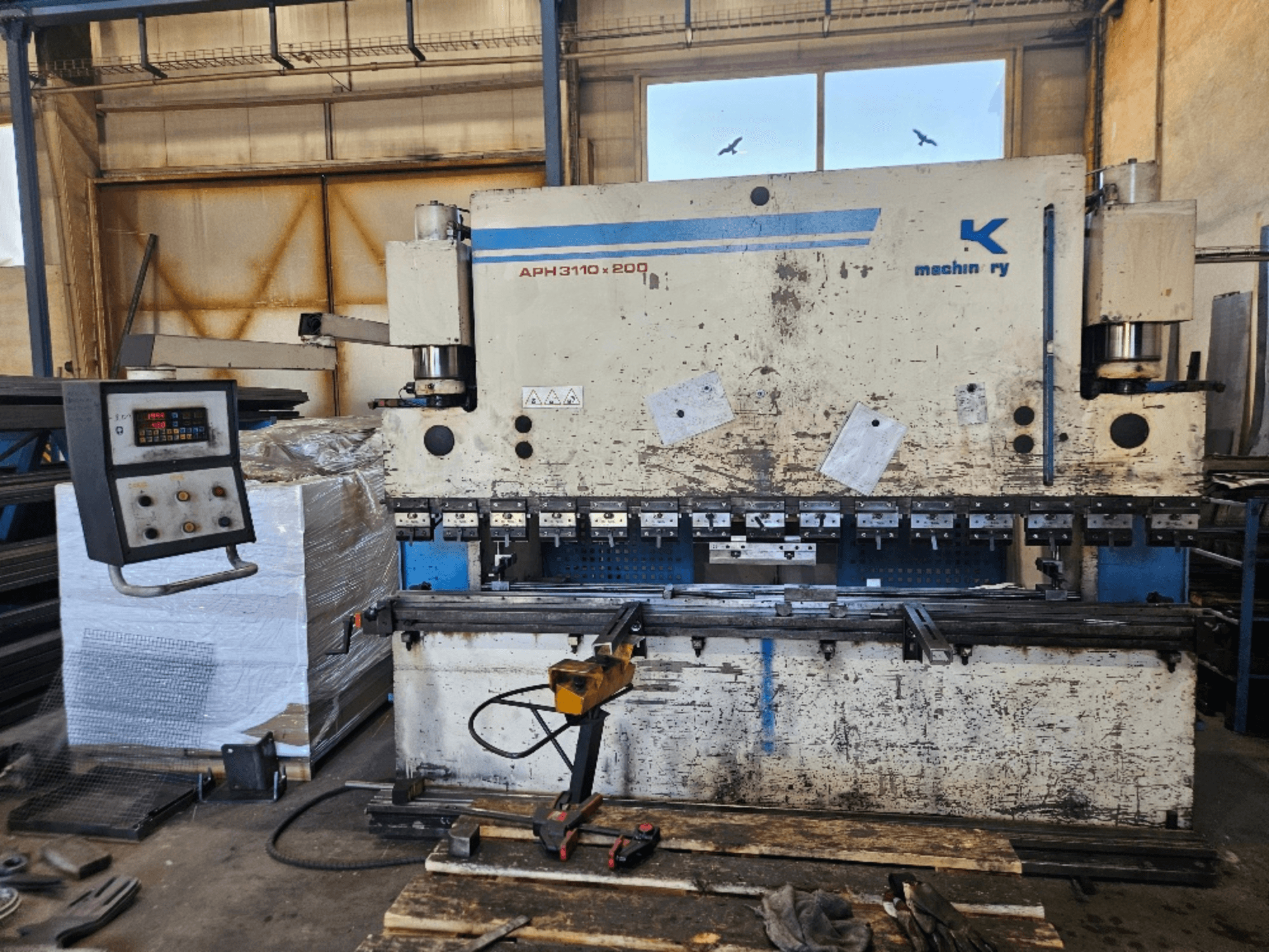 Листогибочный пресс Baykal APH 3110x200 в мастерской, вид спереди, видны панель управления, металлические листы и инструменты.