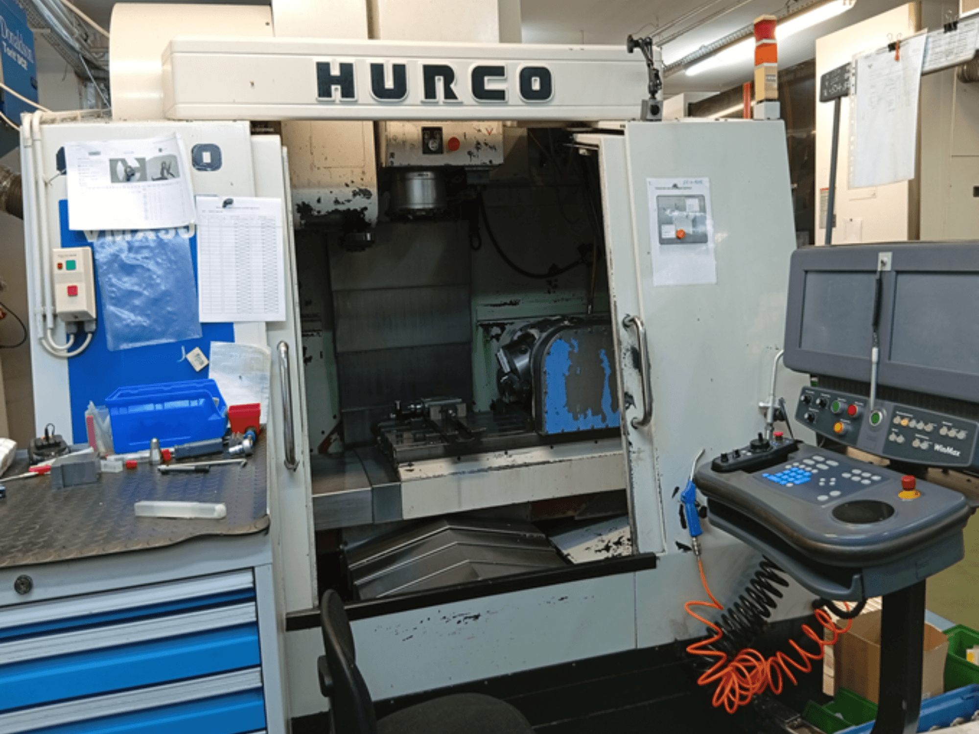 Вертикальный обрабатывающий центр Hurco VMX 30T, вид спереди, панель управления, рабочая зона и частично открытая дверь.