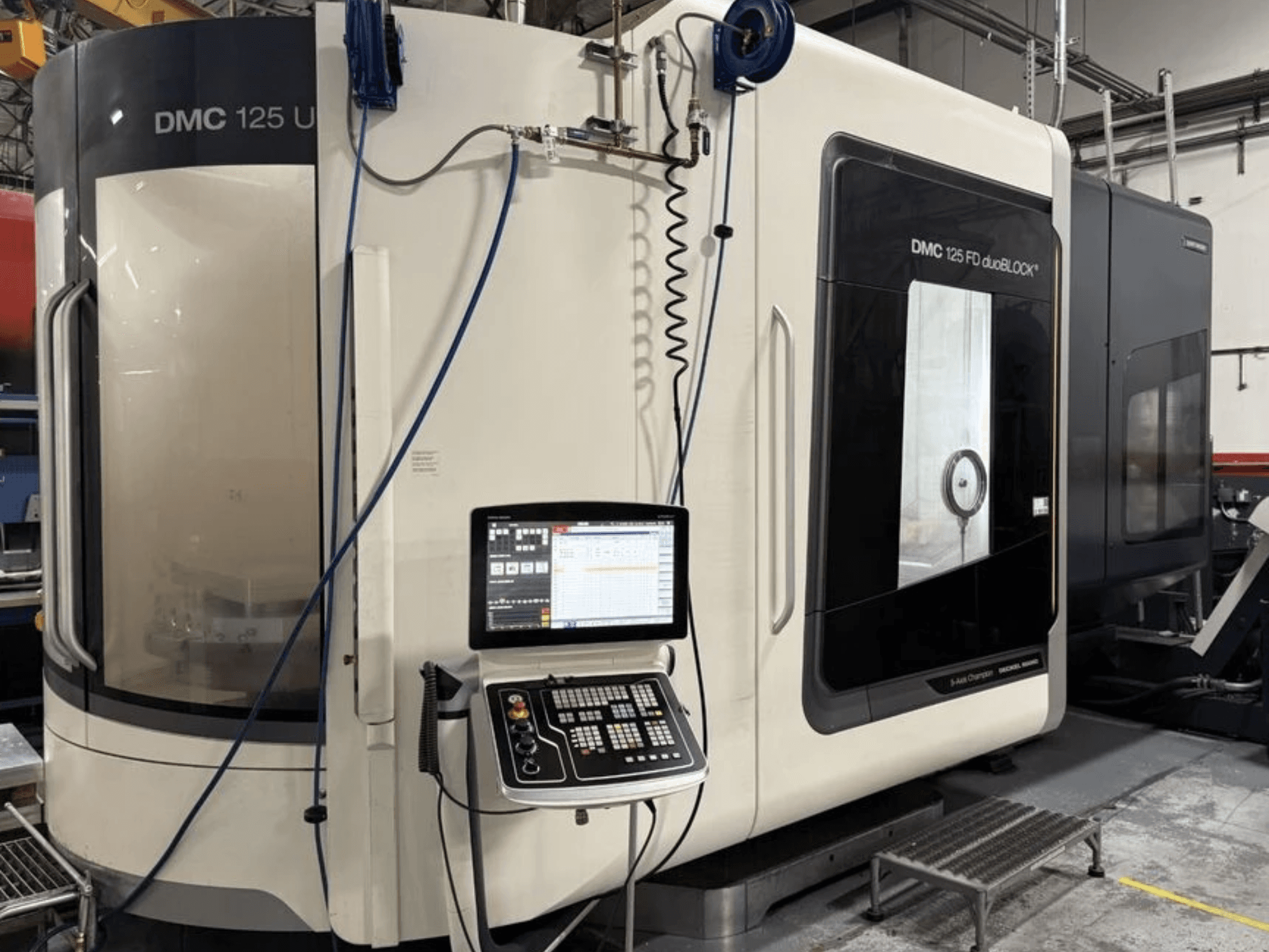 Универсальный обрабатывающий центр DMG MORI DMC 125 U duoBLOCK, вид спереди с панелью управления и отражающими поверхностями.
