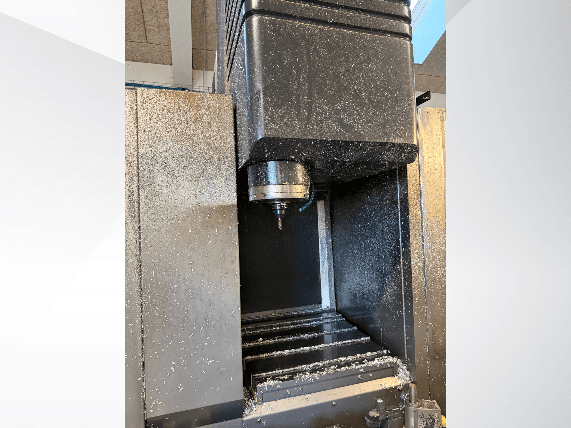 Вертикальный обрабатывающий центр Mazak VTC 300C II, вид спереди, на котором видны шпиндель и стружка, образовавшаяся в процессе обработки.