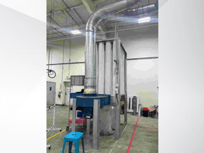 Большая промышленная вентиляционная система, вид спереди, с блестящими металлическими воздуховодами и синим основанием, расположена на просторном складе.