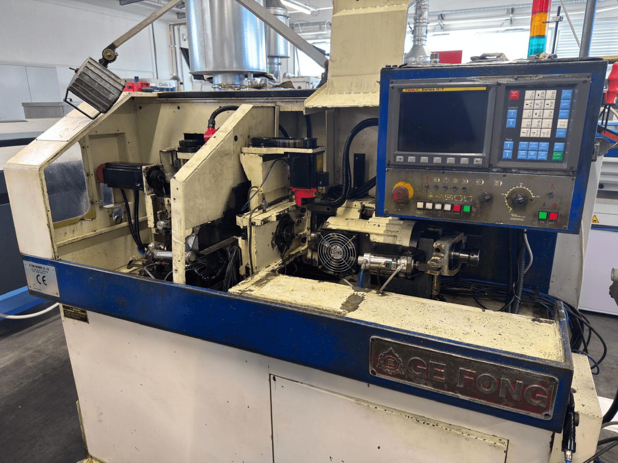 Промышленная машина GE FONG на виде спереди, с изображением внутренних компонентов, панели управления и рабочих частей.