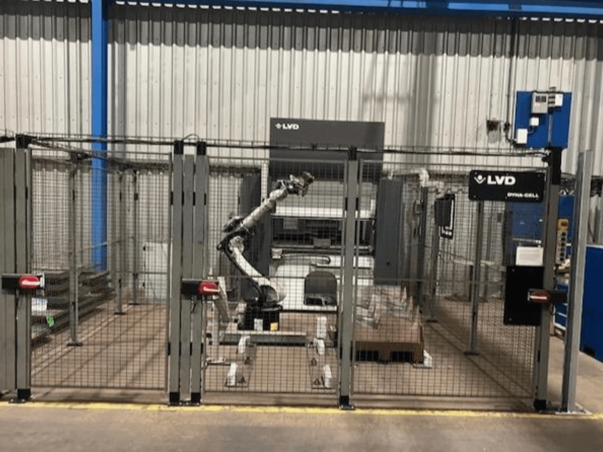 Роботизированная рабочая станция LVD Dyna-Cell в огороженном корпусе, вид спереди, с роботизированной рукой и панелью управления.