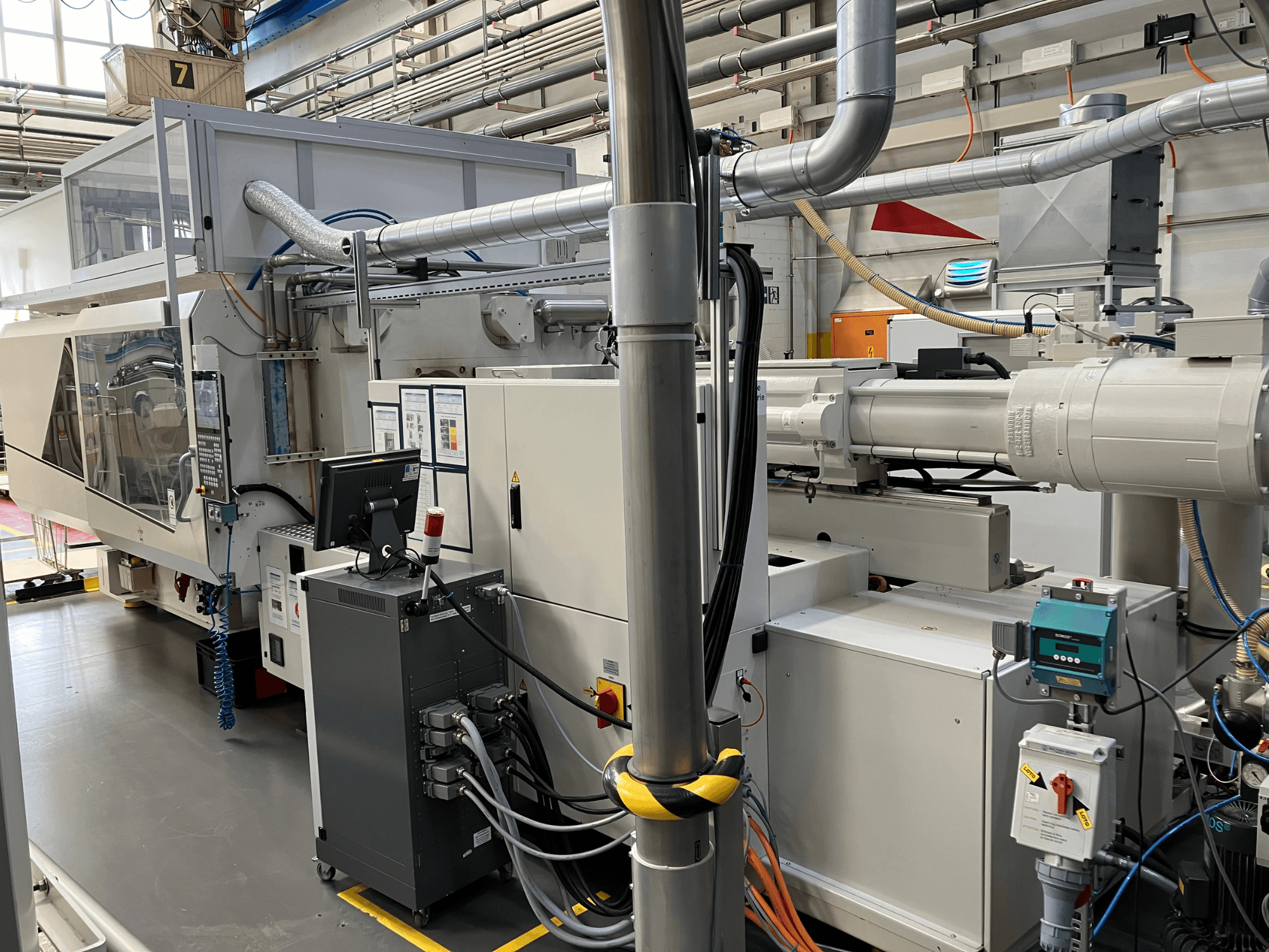 Промышленное оборудование с панелью управления, вид спереди, с изображением труб, электрических компонентов и элементов безопасности.