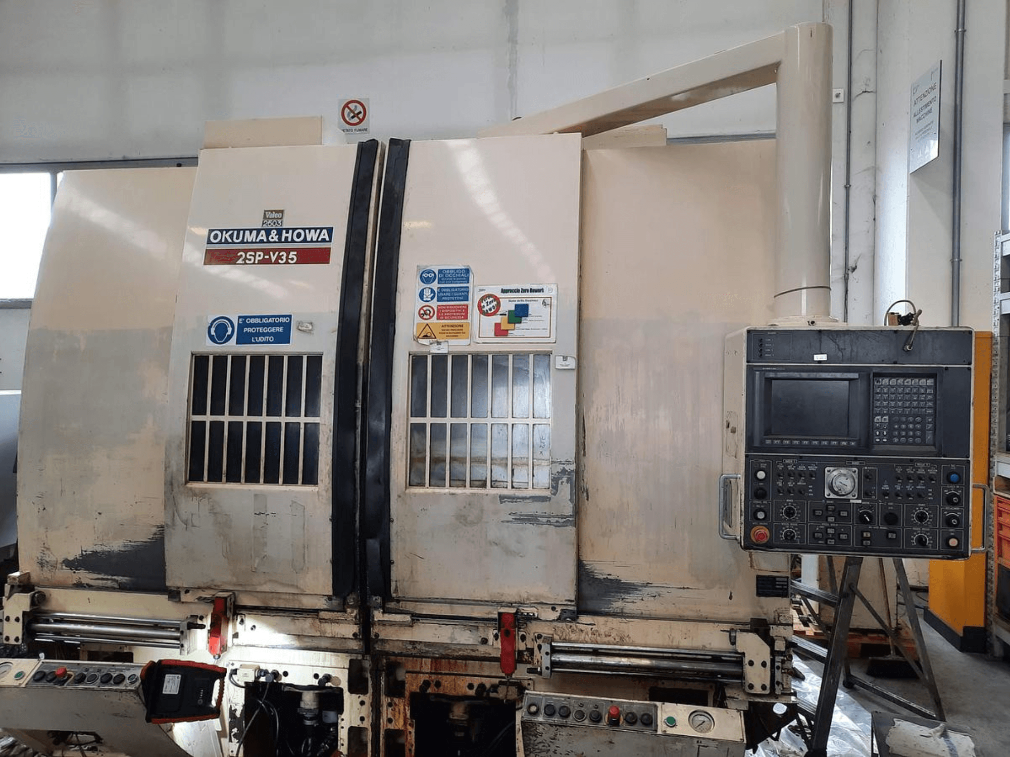 Станок с ЧПУ OKUMA & HOWA 2SP-V35, вид спереди, панель управления с различными кнопками и наклейками безопасности.