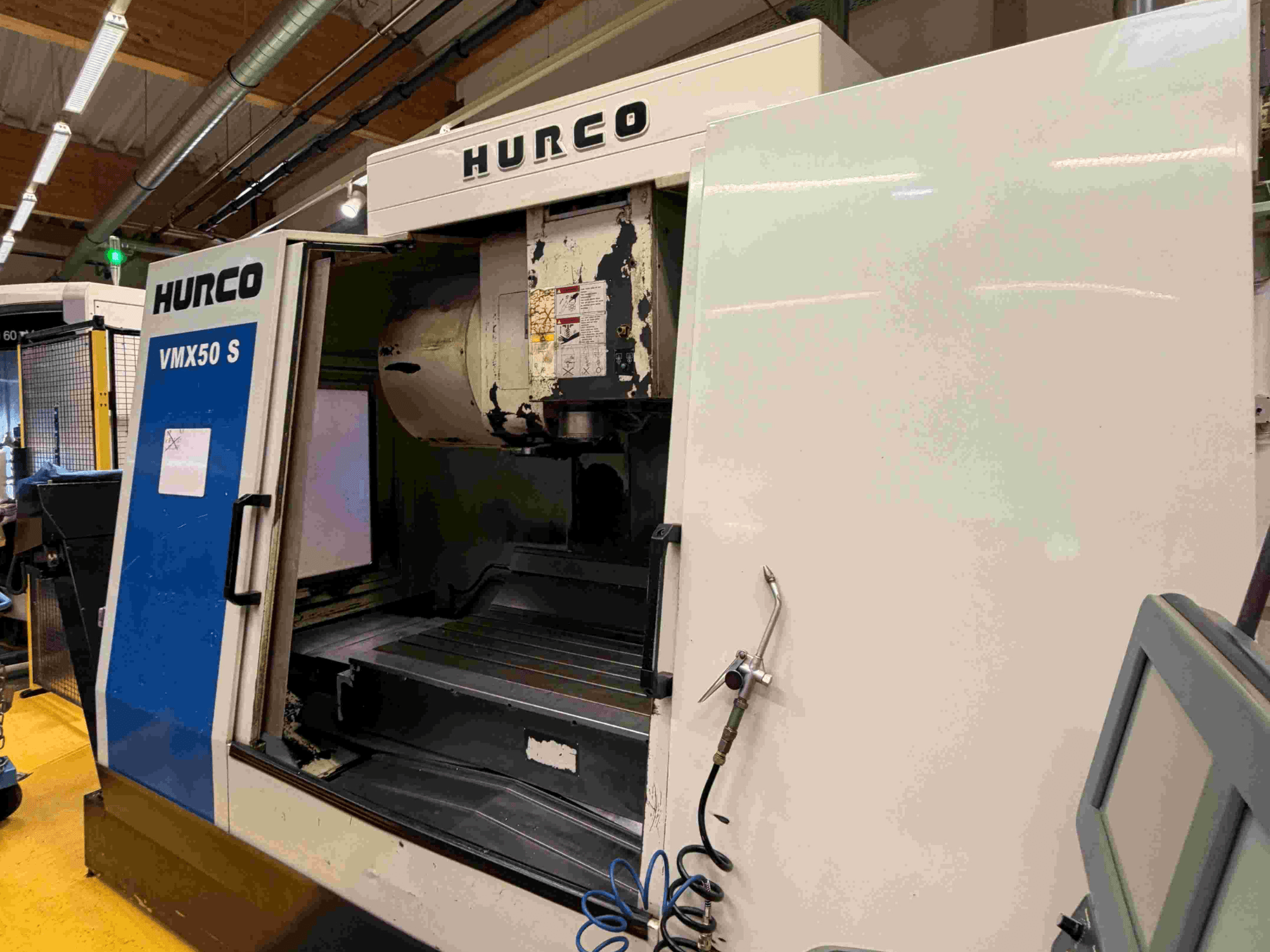 Вертикальный обрабатывающий центр Hurco VMX50 S, вид сбоку, демонстрирует открытую дверь и панель управления.