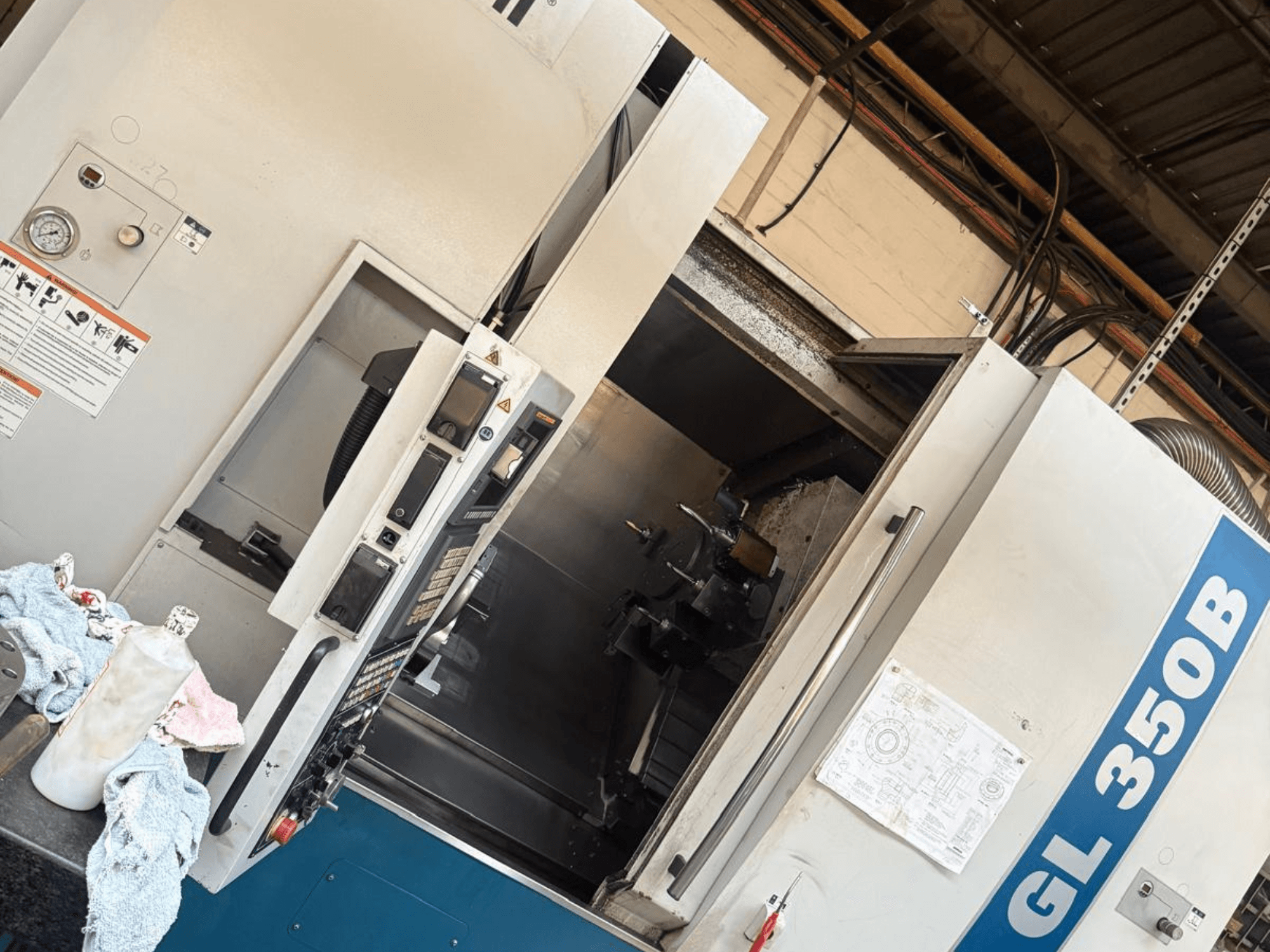 Горизонтальный токарный станок Romi GL 350B, вид спереди, панель управления и открытая дверь, открывающая внутреннее пространство.