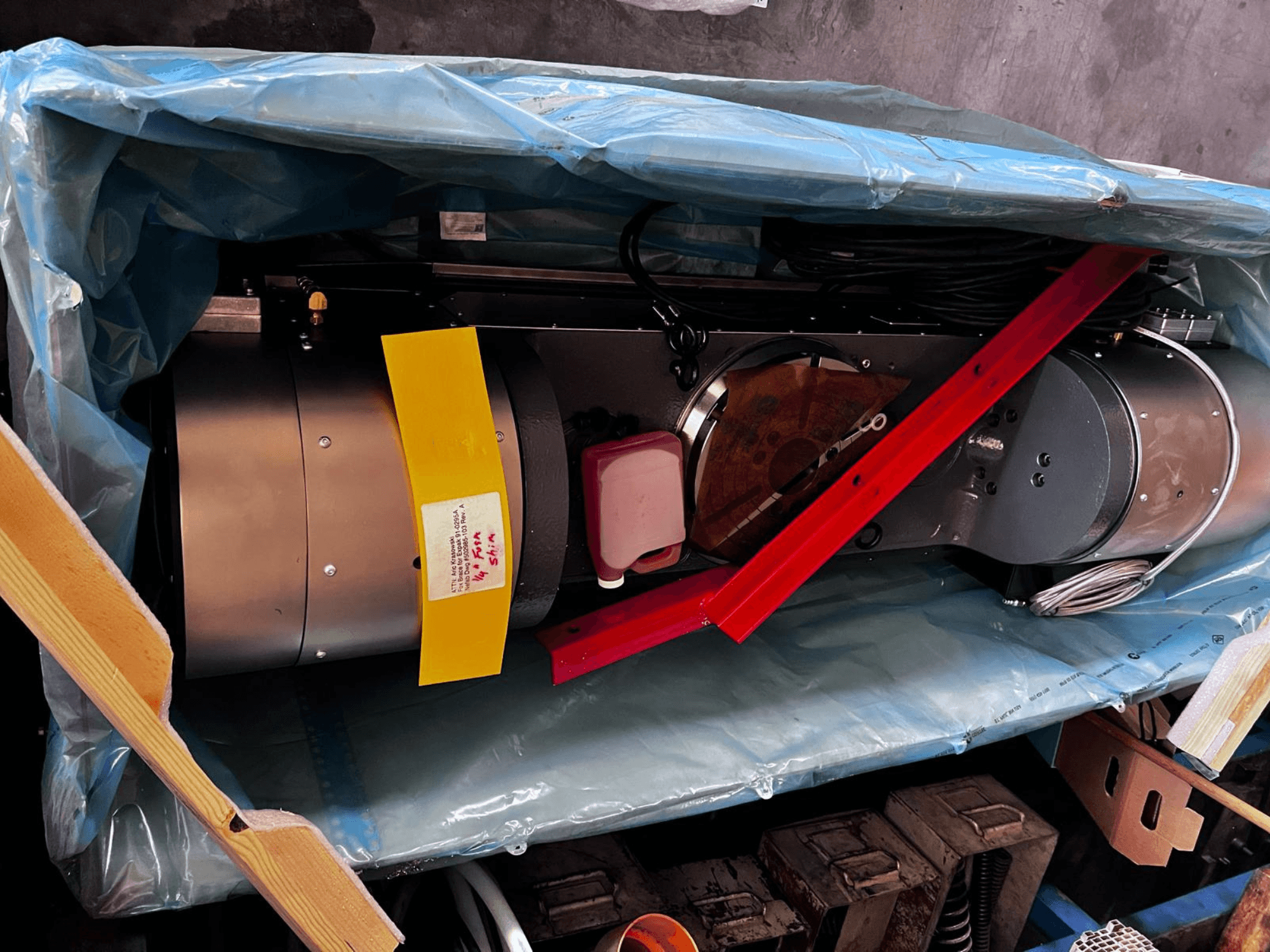 Устройство двигателя, частично видимое в упаковке, имеет серебристый внешний вид, разноцветные датчики и красную опорную скобу.