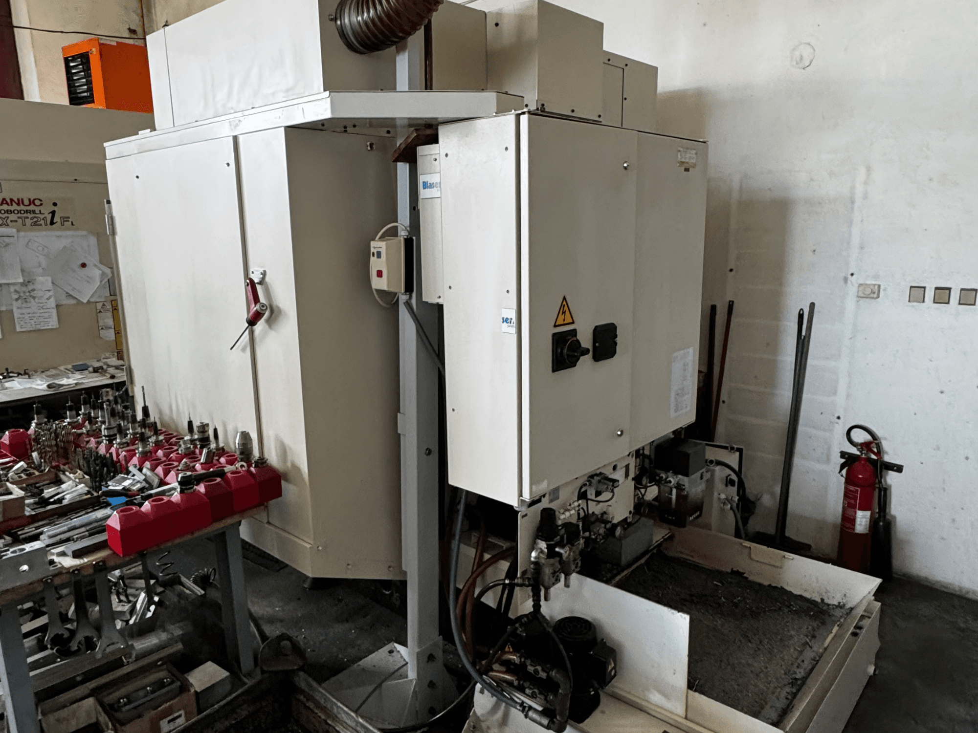 Вертикальный обрабатывающий центр FANUC Robodrill alpha-T21iFL, вид сбоку, демонстрирующий панель управления, инструменты и рабочую зону.