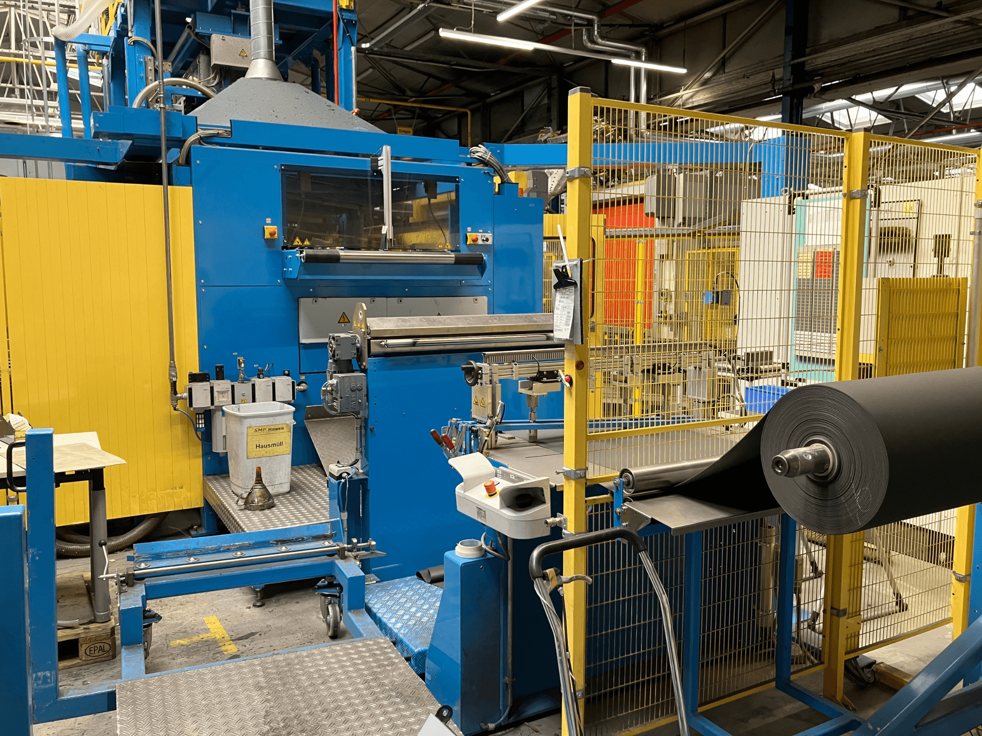 Машина для переработки пластмасс KIEFEL KLS 86/235 с видом спереди, с рулоном черного материала и панелью управления.