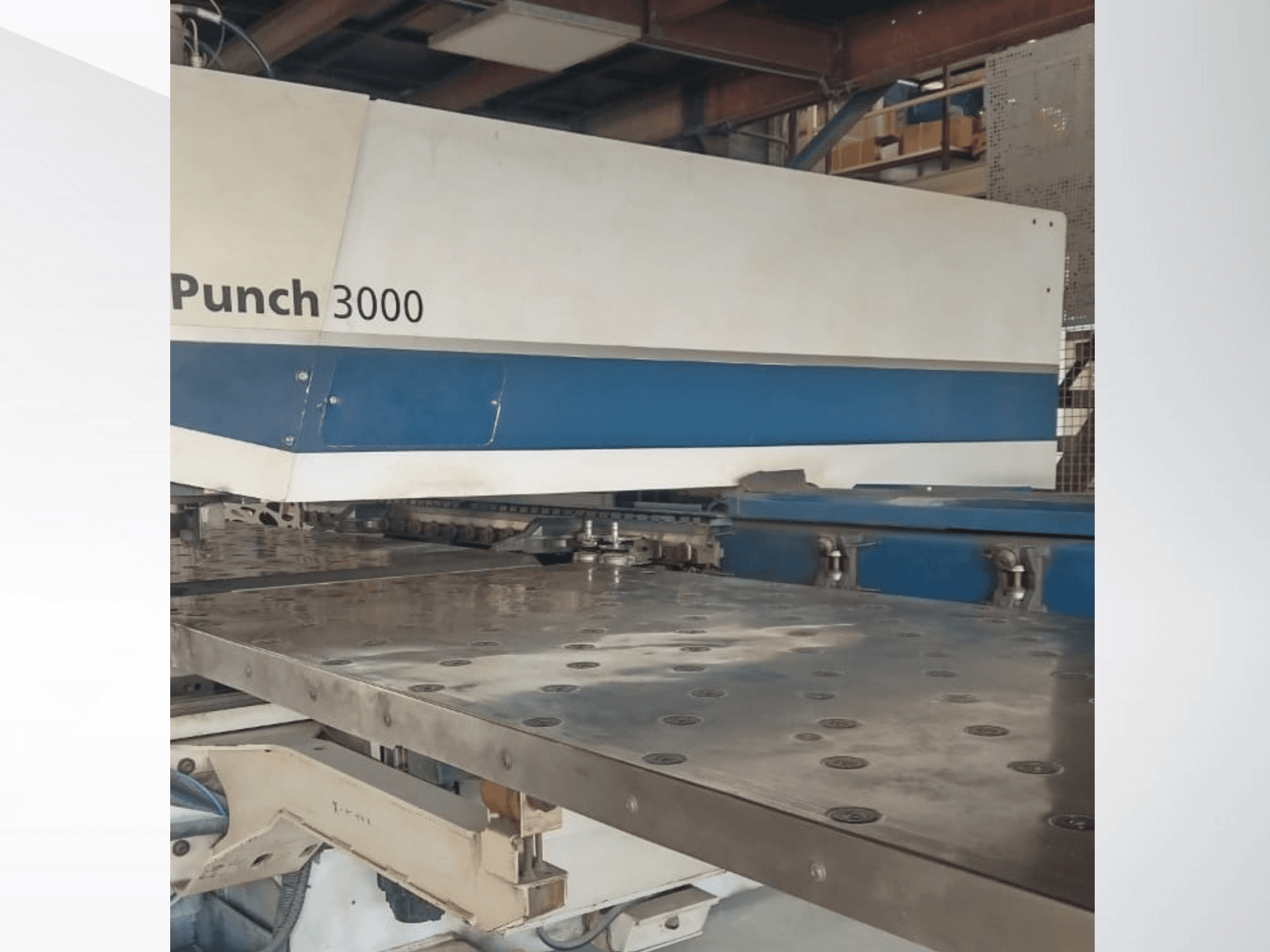Станок Punch 3000 в мастерской, вид спереди, демонстрирует большую плоскую металлическую поверхность с множеством пробитых отверстий.