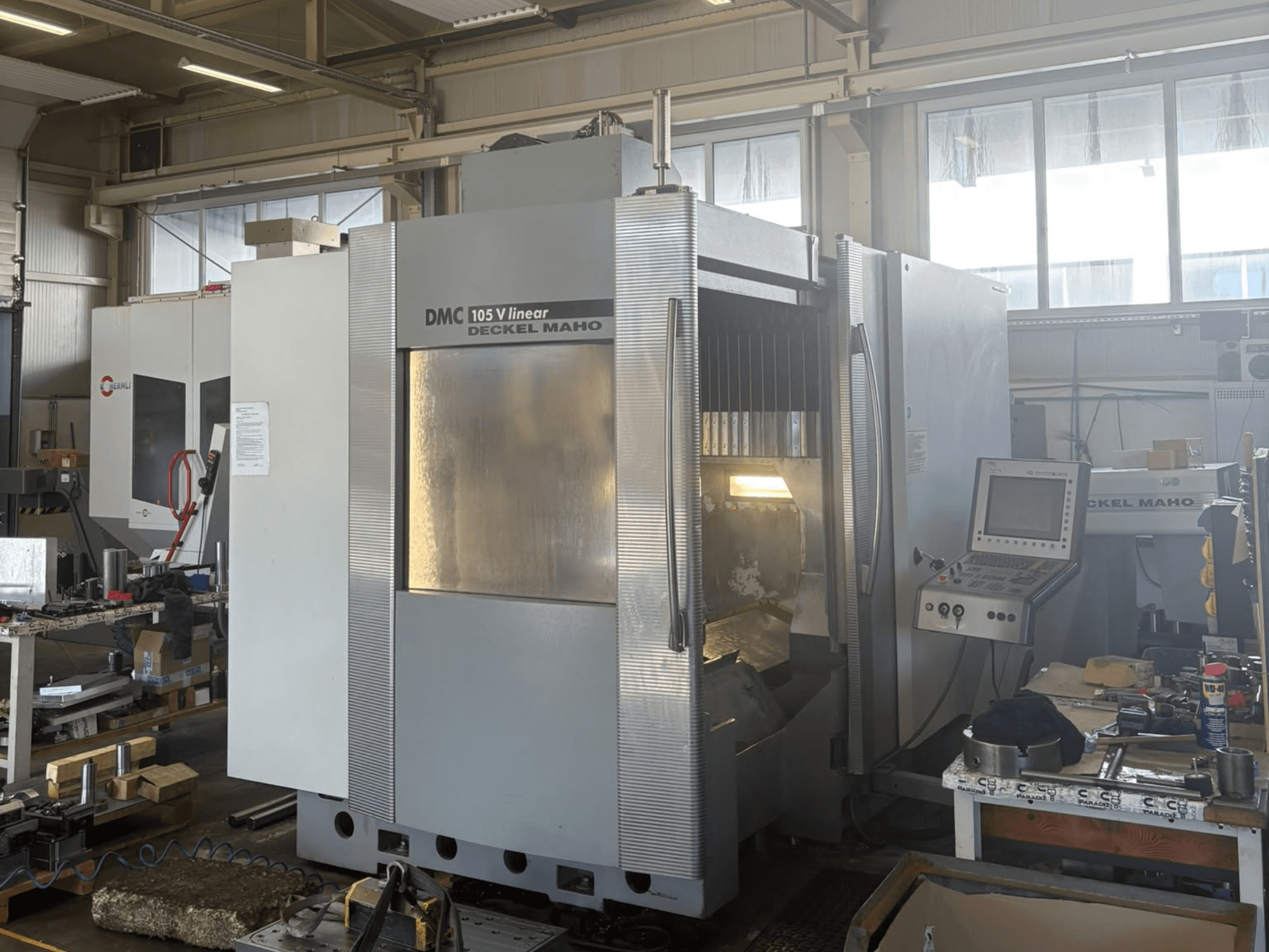 DMG DECKEL MAHO DMU 105 V — линейный вертикальный обрабатывающий центр, вид спереди с панелью управления и рабочей зоной.