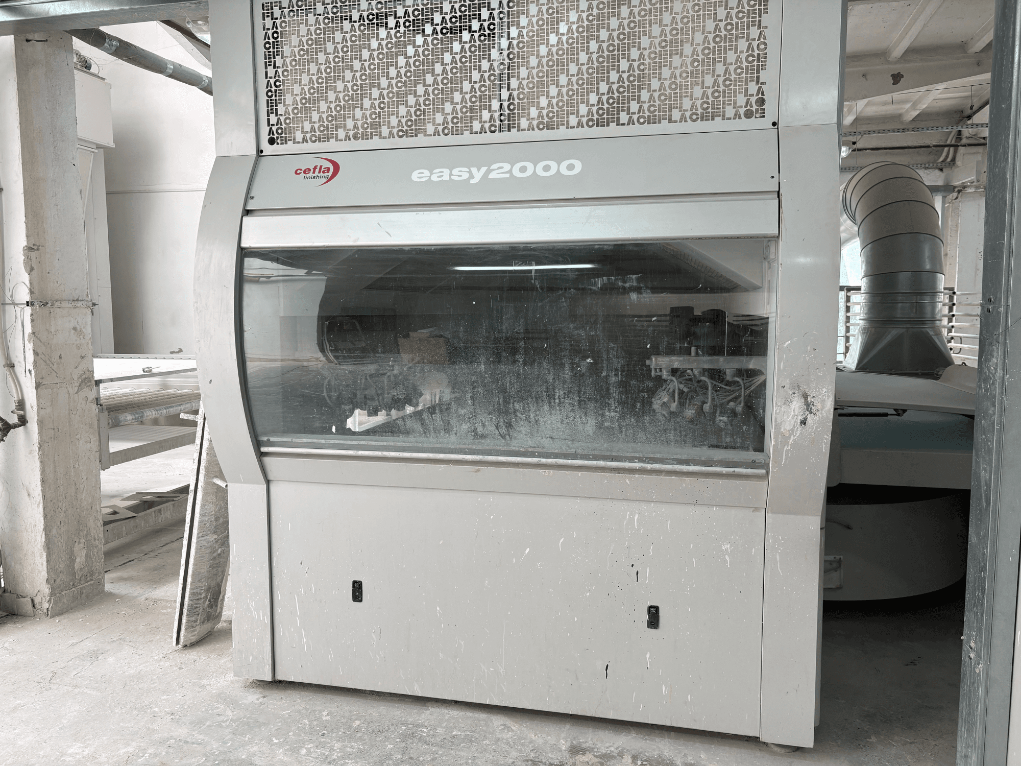 Машина Cefla EASY 2000 D в виде спереди: с большой прозрачной панелью, запыленной поверхностью и видимыми внутренними компонентами.