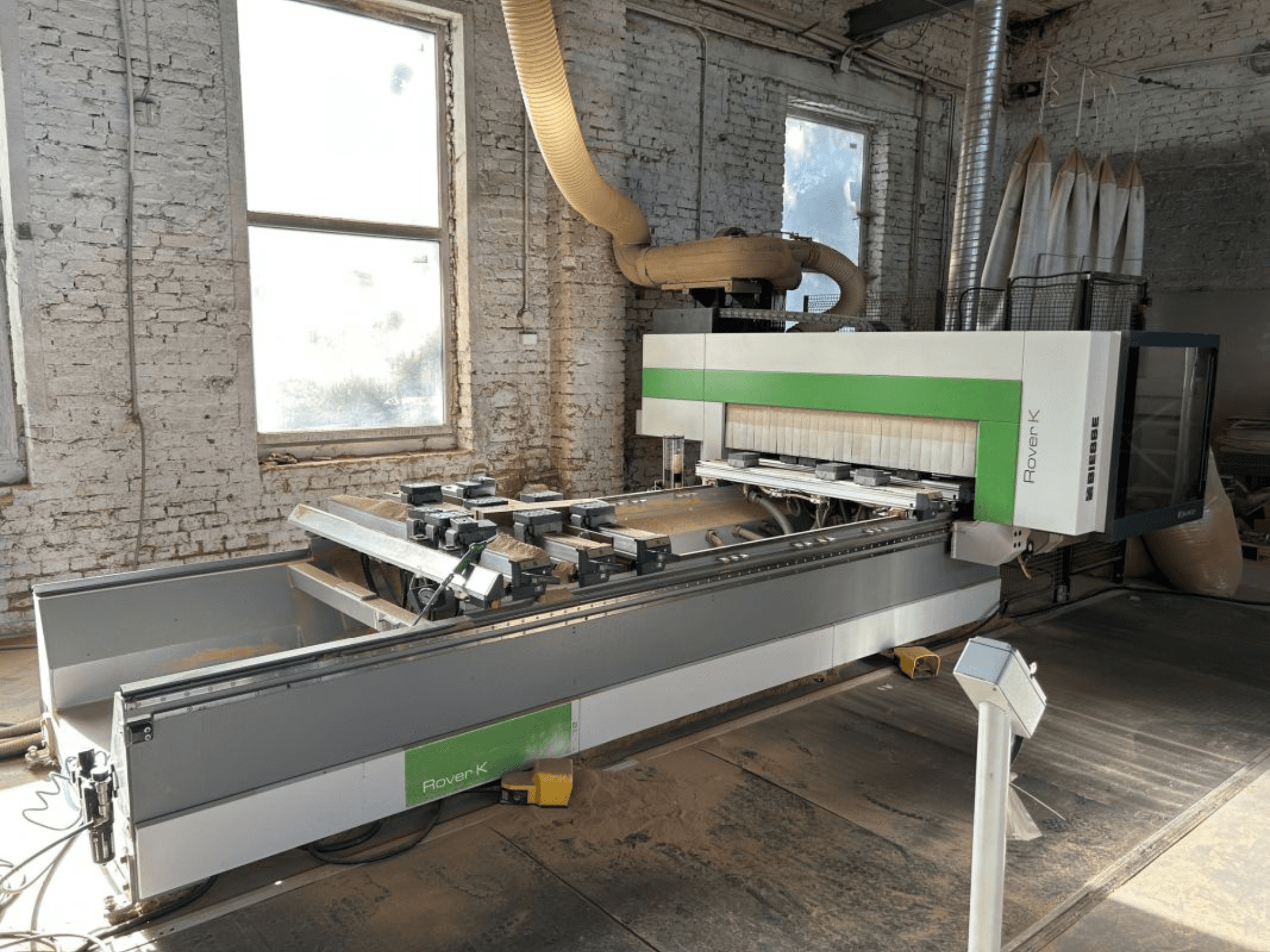 Обрабатывающий центр с ЧПУ BIESSE Rover K 1532 G в цехе, вид спереди, на котором видны режущие инструменты и рабочая поверхность.