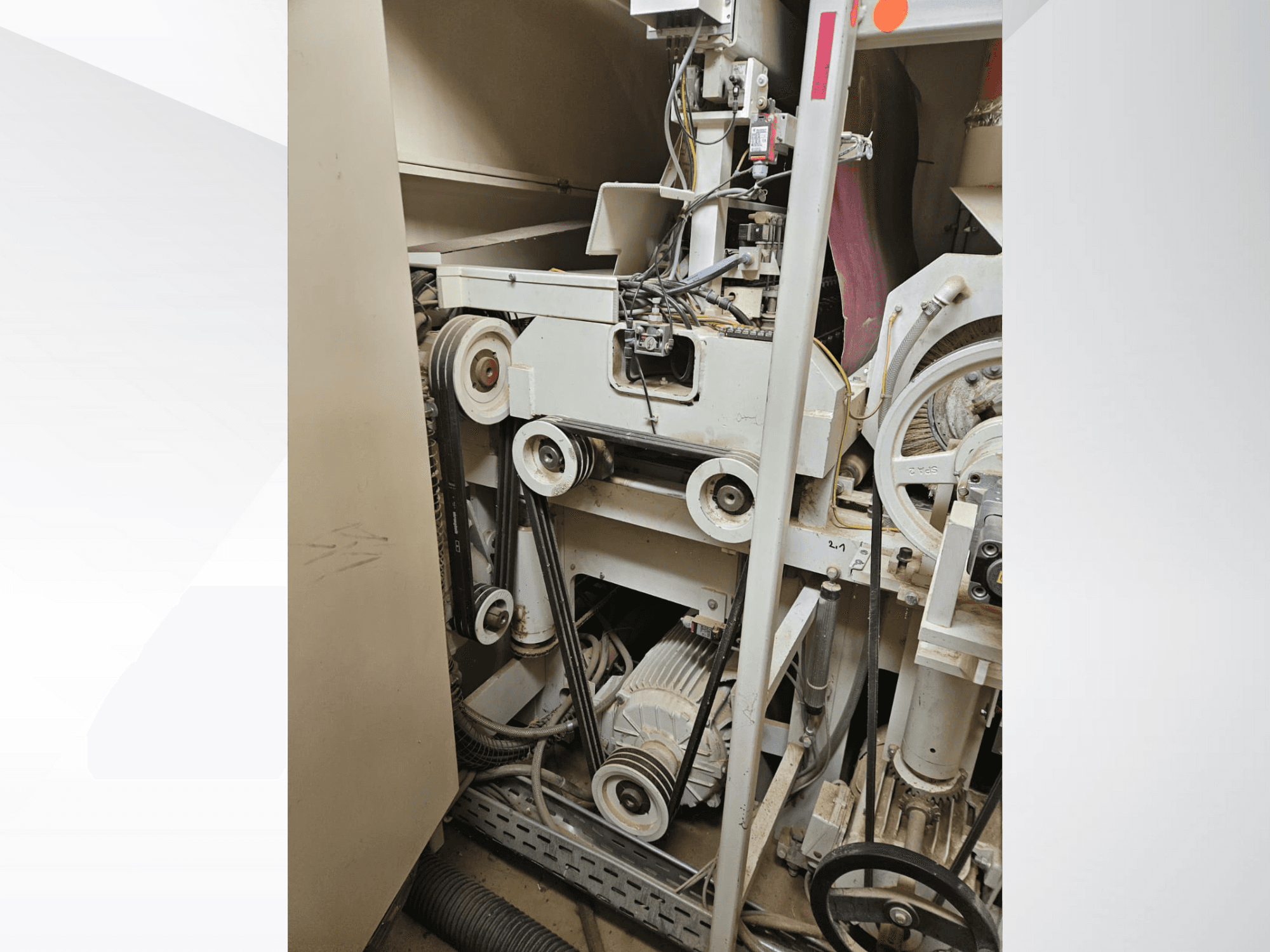 Интерьер промышленного станка с ремнями и шкивами, с изображением двигателя и проводки, вид сбоку.