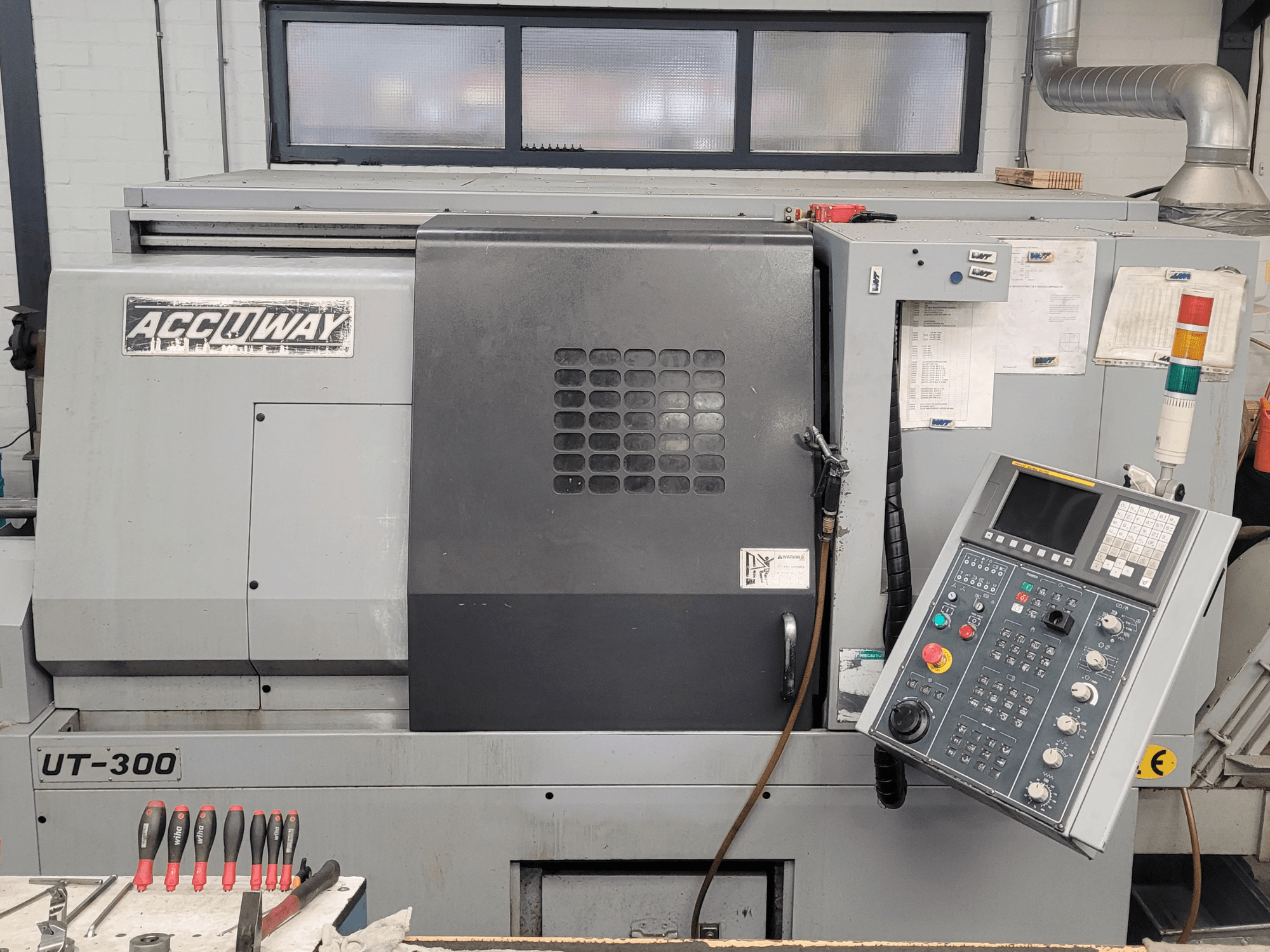 Станок с ЧПУ Accuway UT-300 с видом спереди, с панелью управления и различными кнопками управления, в мастерской.