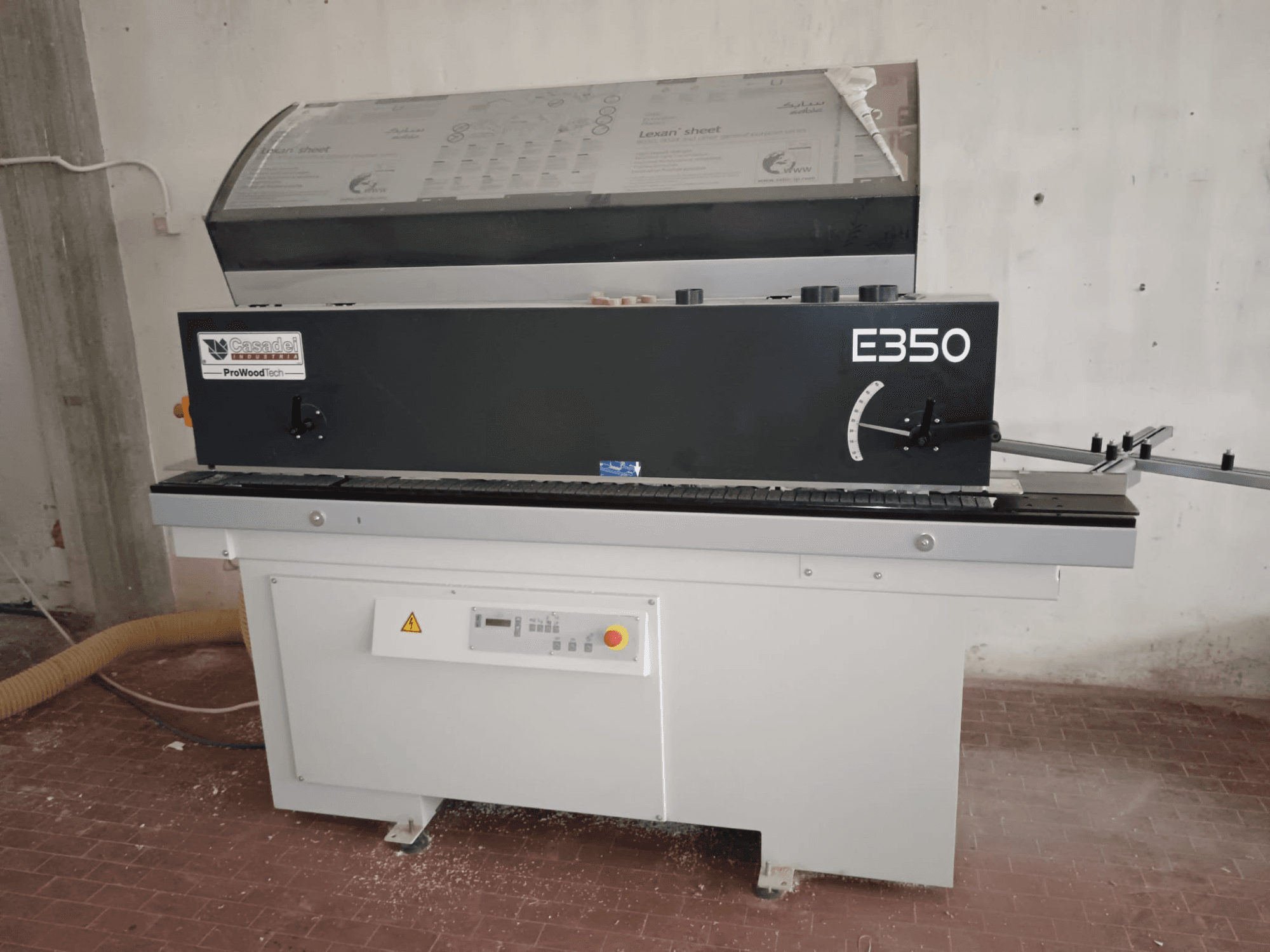 Cesaroli ProWoodtech E350, вид сбоку на деревообрабатывающий станок с панелью управления и накопителем пыли, установленный на белом основании.