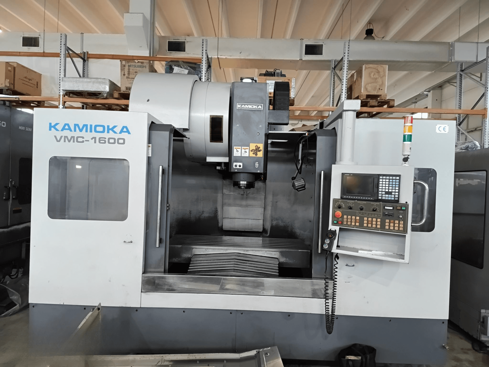 Вертикальный обрабатывающий центр Kamioka VMC-1600 в заводских условиях, вид спереди с панелью управления и видимой обрабатывающей станиной.