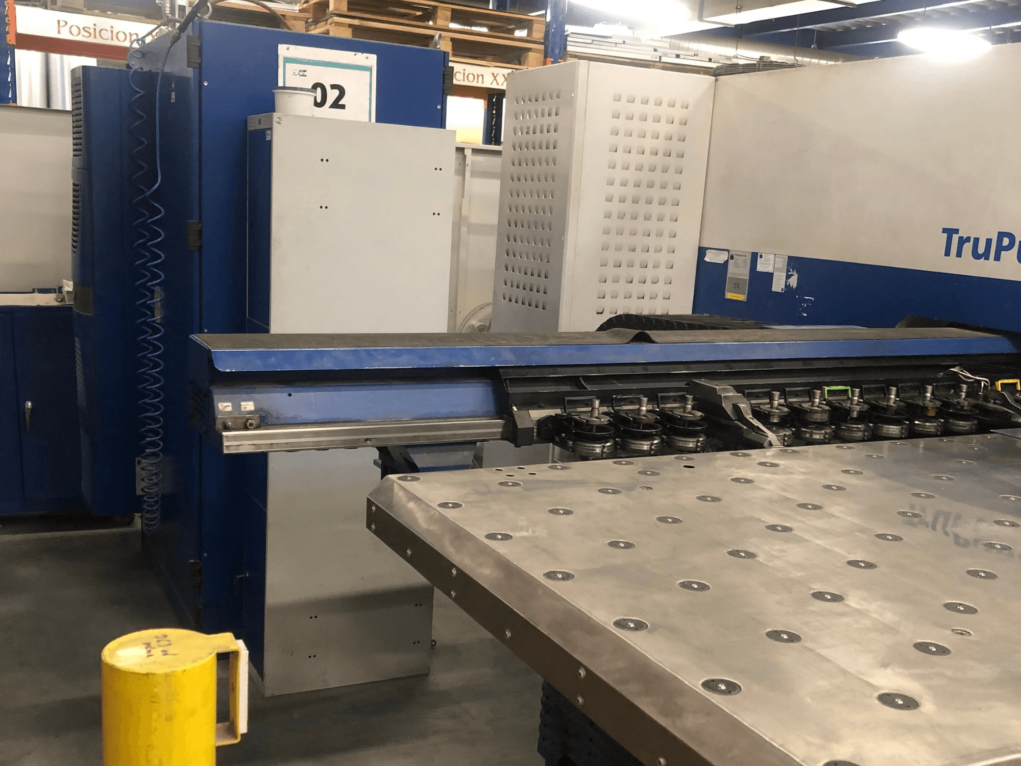 Штамповочный станок с ЧПУ TRUMPF TruPunch 5000, вид спереди с изображением инструментальной револьверной головки и панели управления, рядом — металлический рабочий стол.