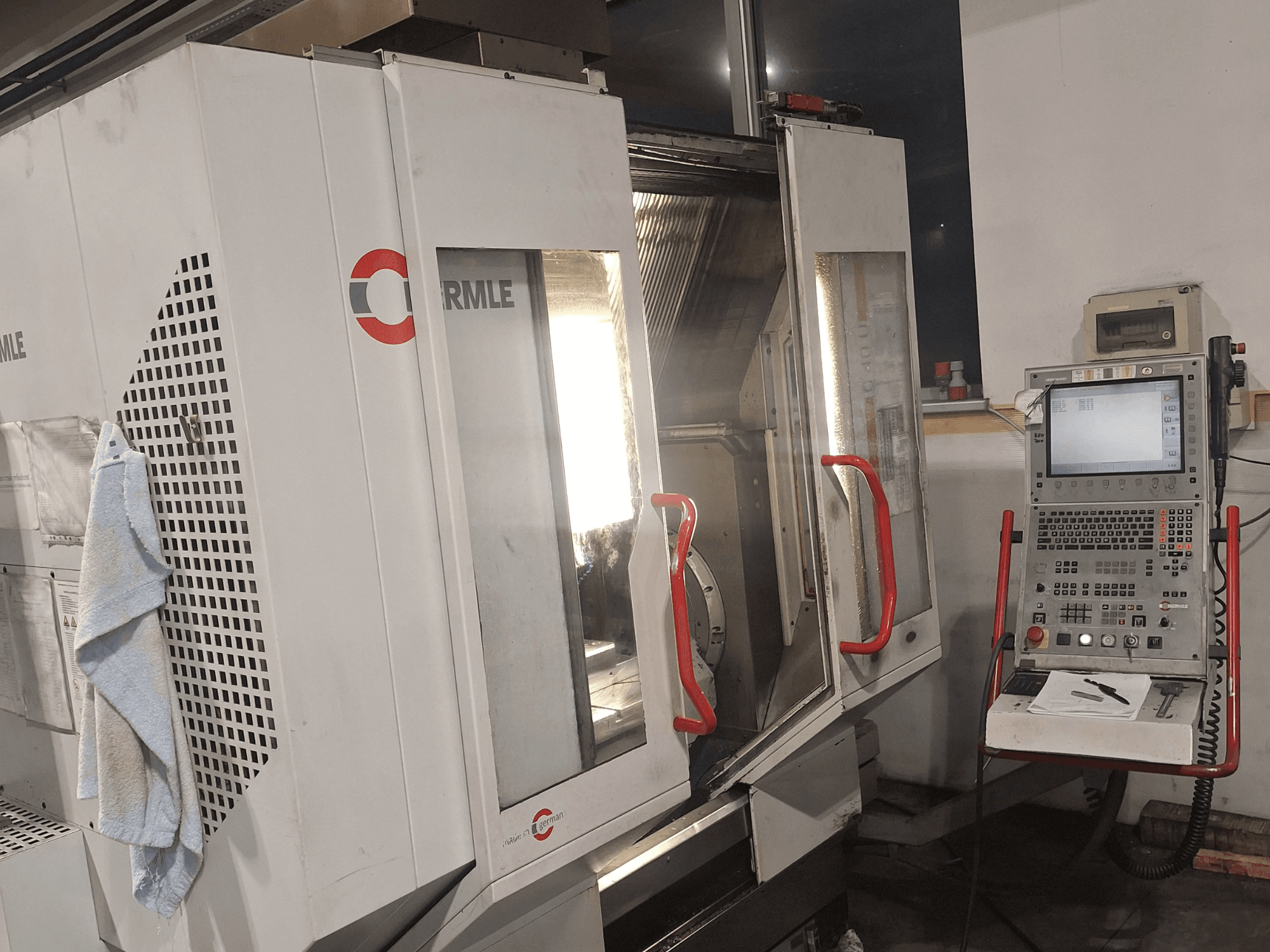 Станок с ЧПУ марки Cormile, вид спереди с частично открытыми дверцами и панелью управления с экраном и кнопками.