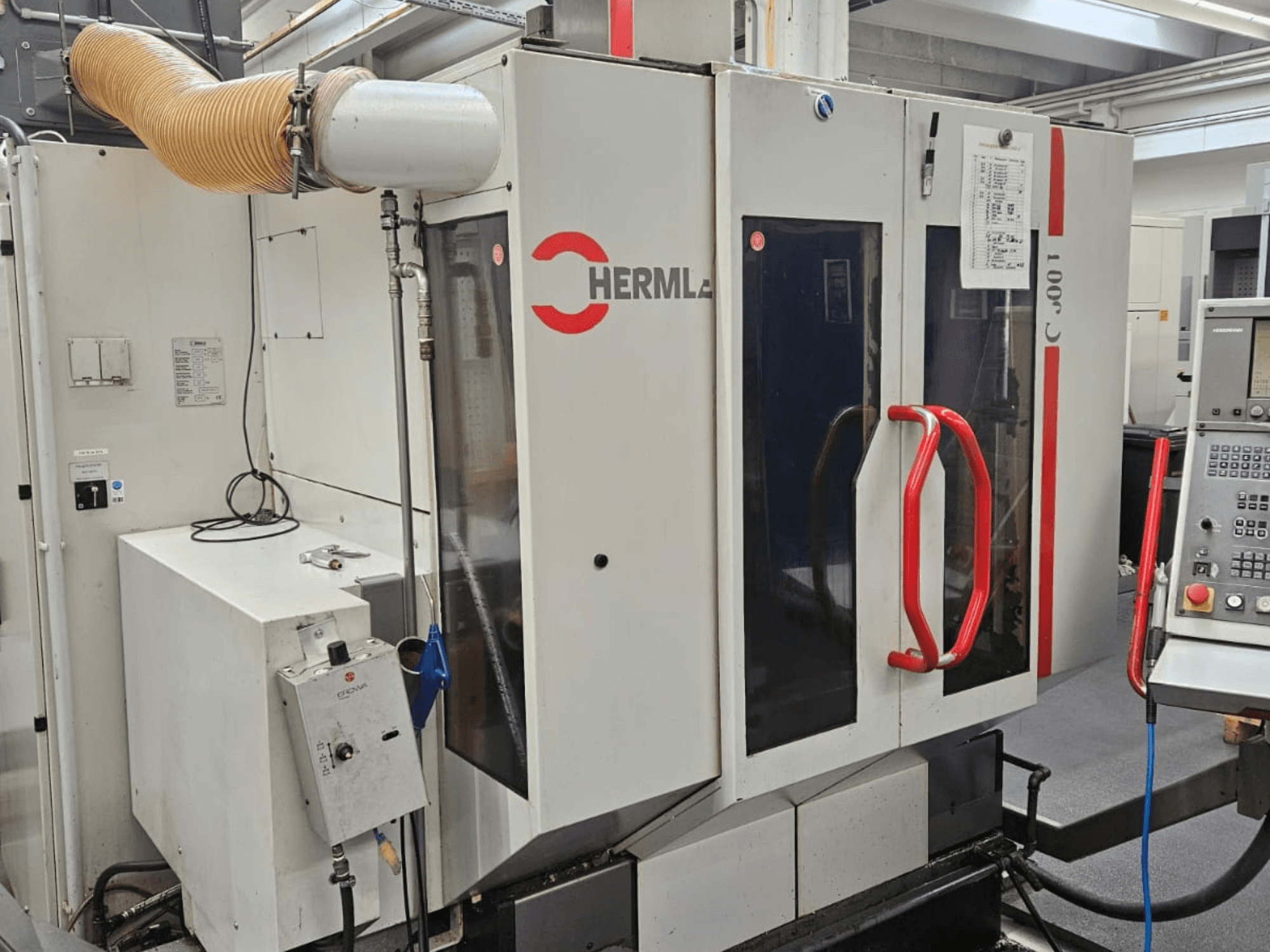 Вид спереди универсального обрабатывающего центра HERMLE C 600 U, панель управления и красные ручки на дверях.