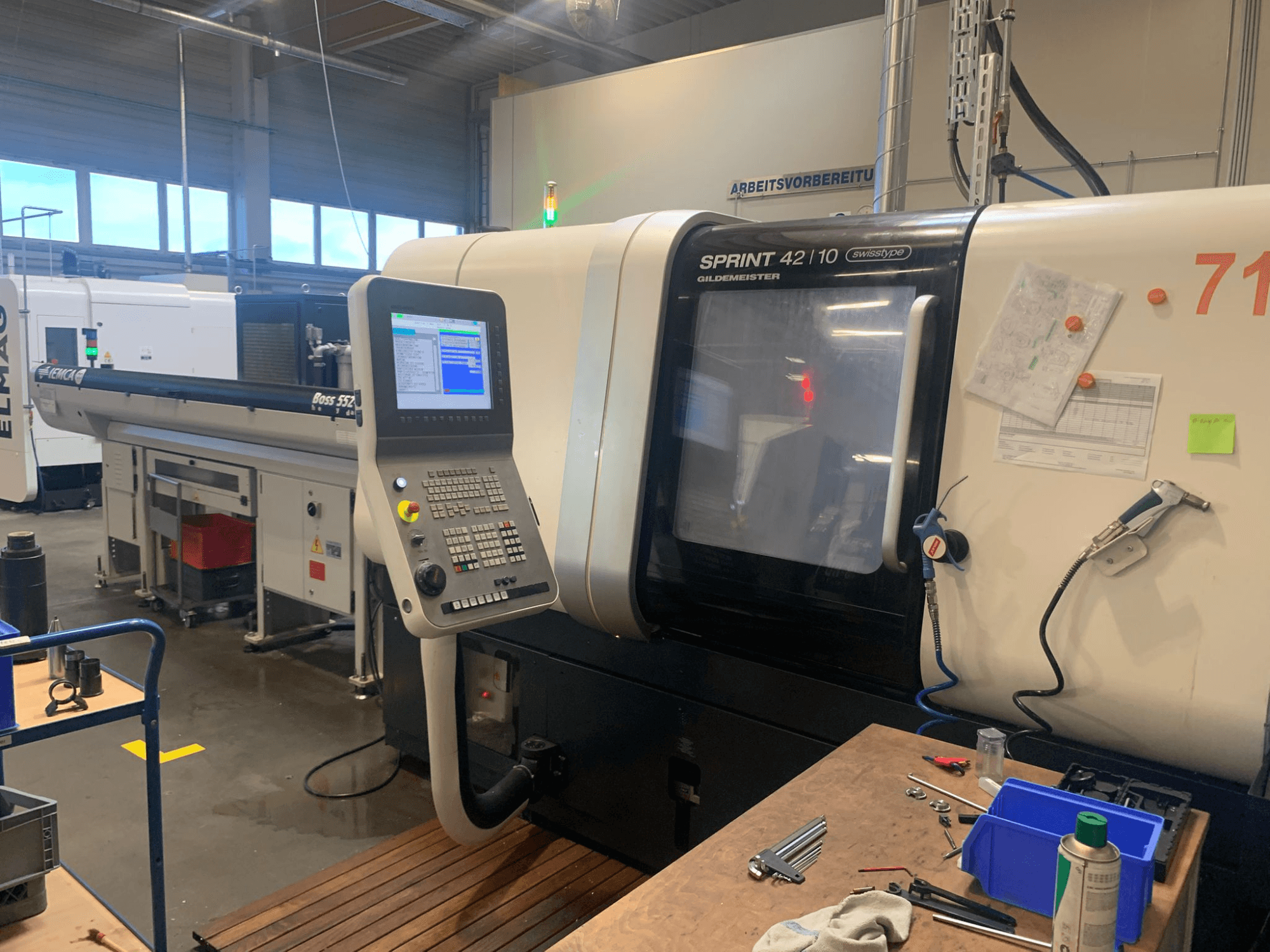 Линейный токарный станок швейцарского типа DMG MORI Sprint 42/10, вид спереди, панель управления и загромождение рабочего пространства.