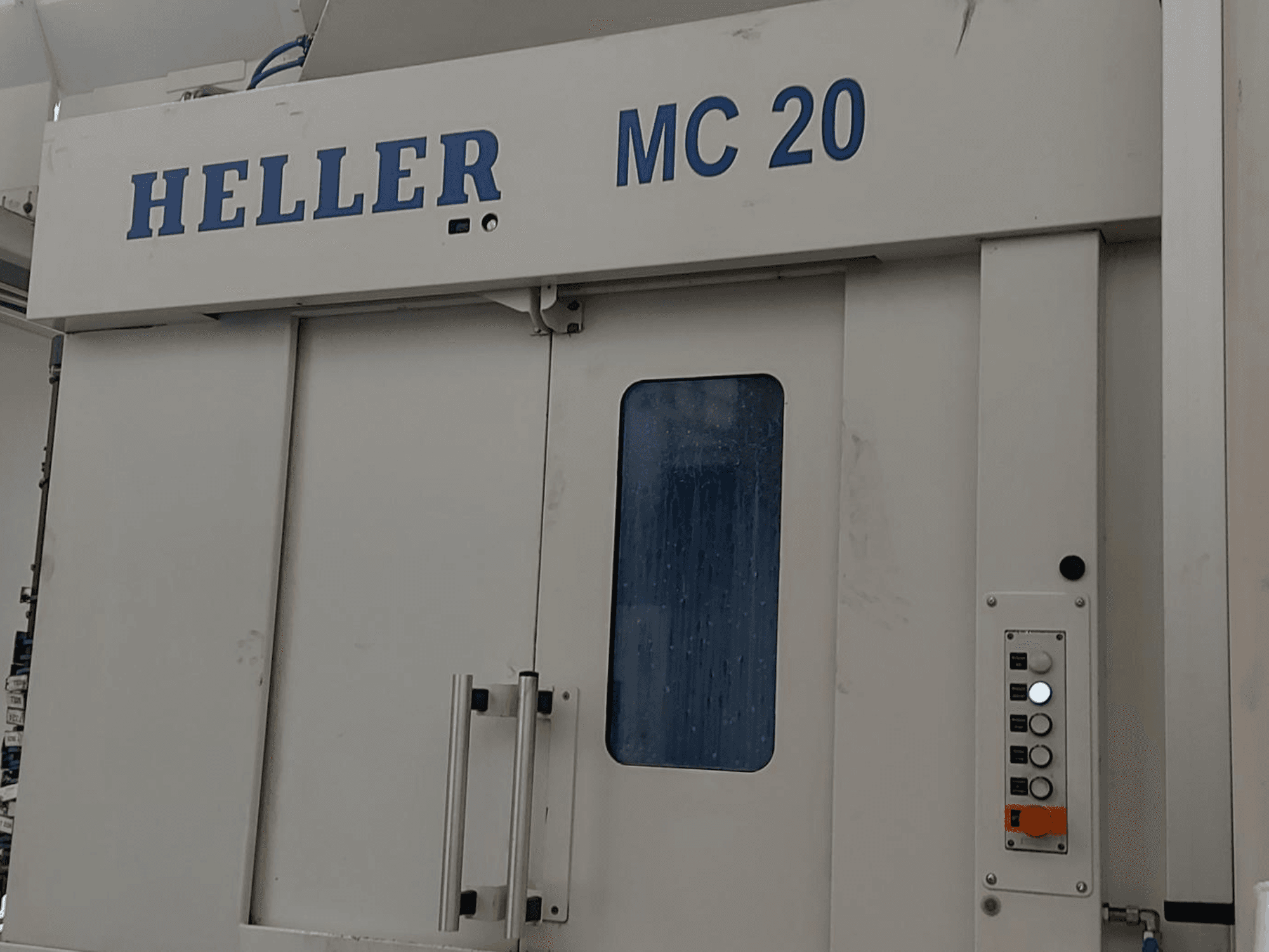Вид спереди горизонтального обрабатывающего центра HELLER MC 20 с панелью управления и передним окном.