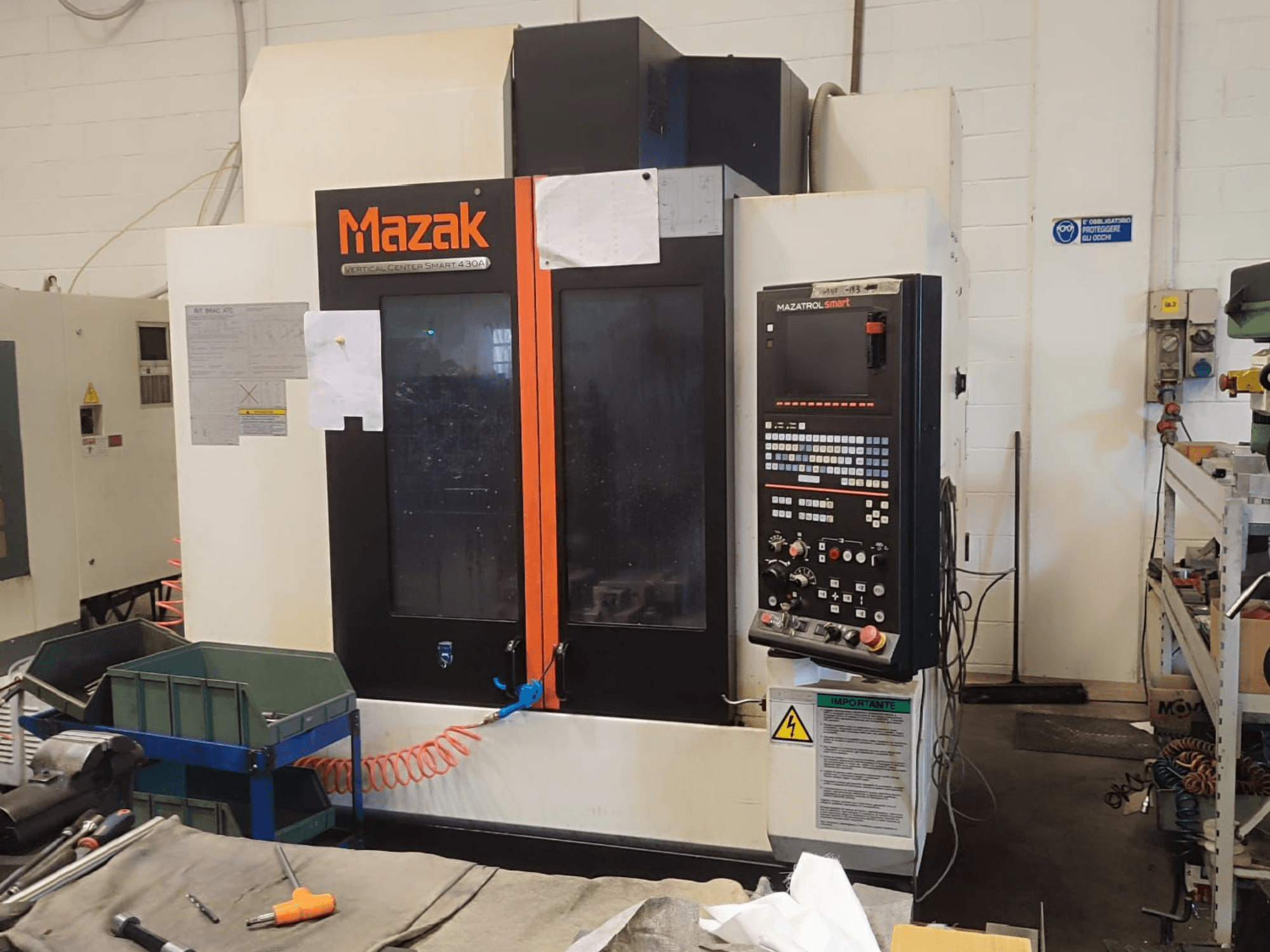 Вертикальный обрабатывающий центр Mazak VCS 430A, вид спереди, демонстрирующий панель управления и рабочие детали в условиях мастерской.