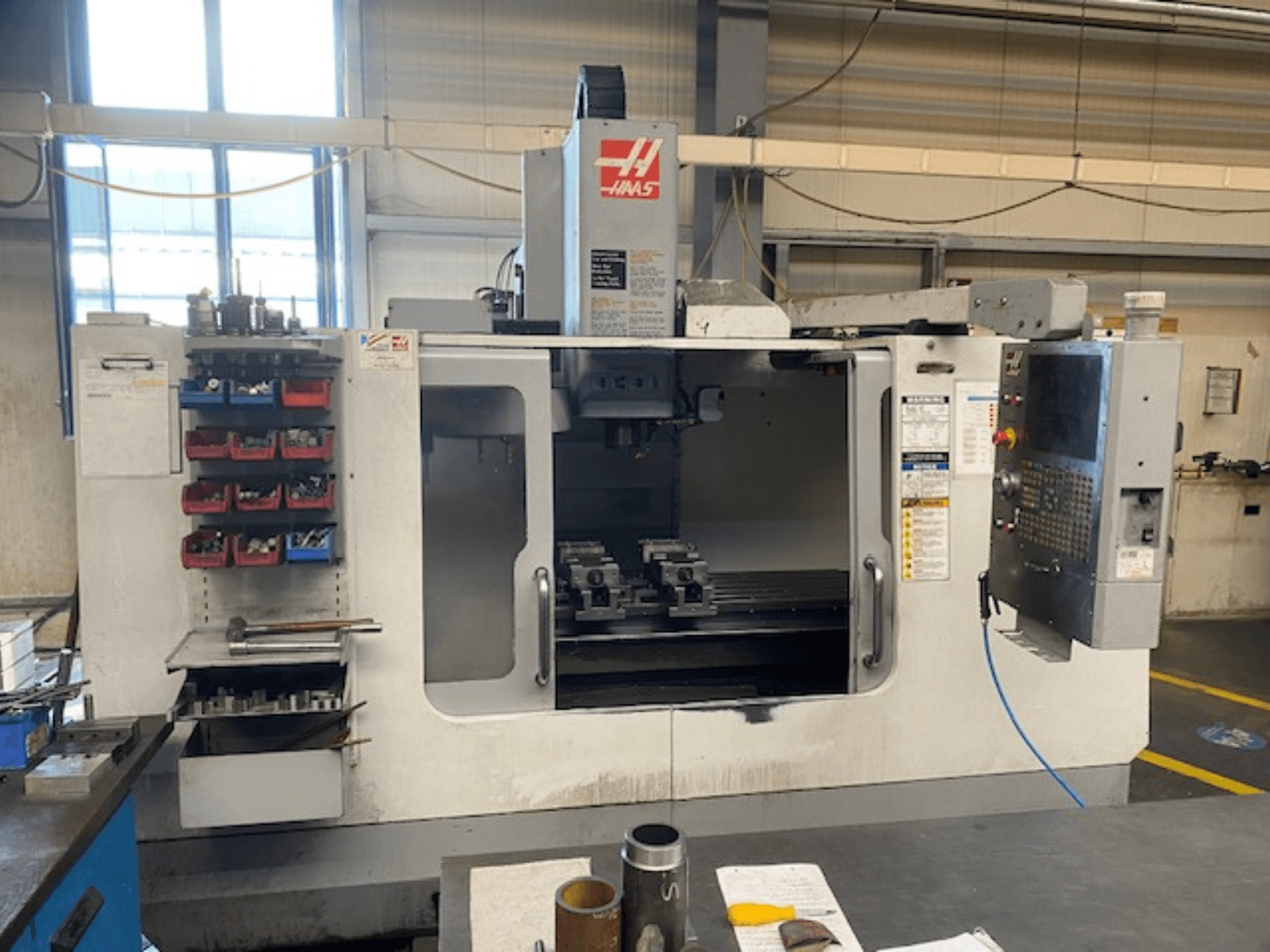 Фрезерный станок с ЧПУ Haas, модель VF-2, вид спереди, видны хранилище инструментов, панель управления и инструменты рабочей зоны.