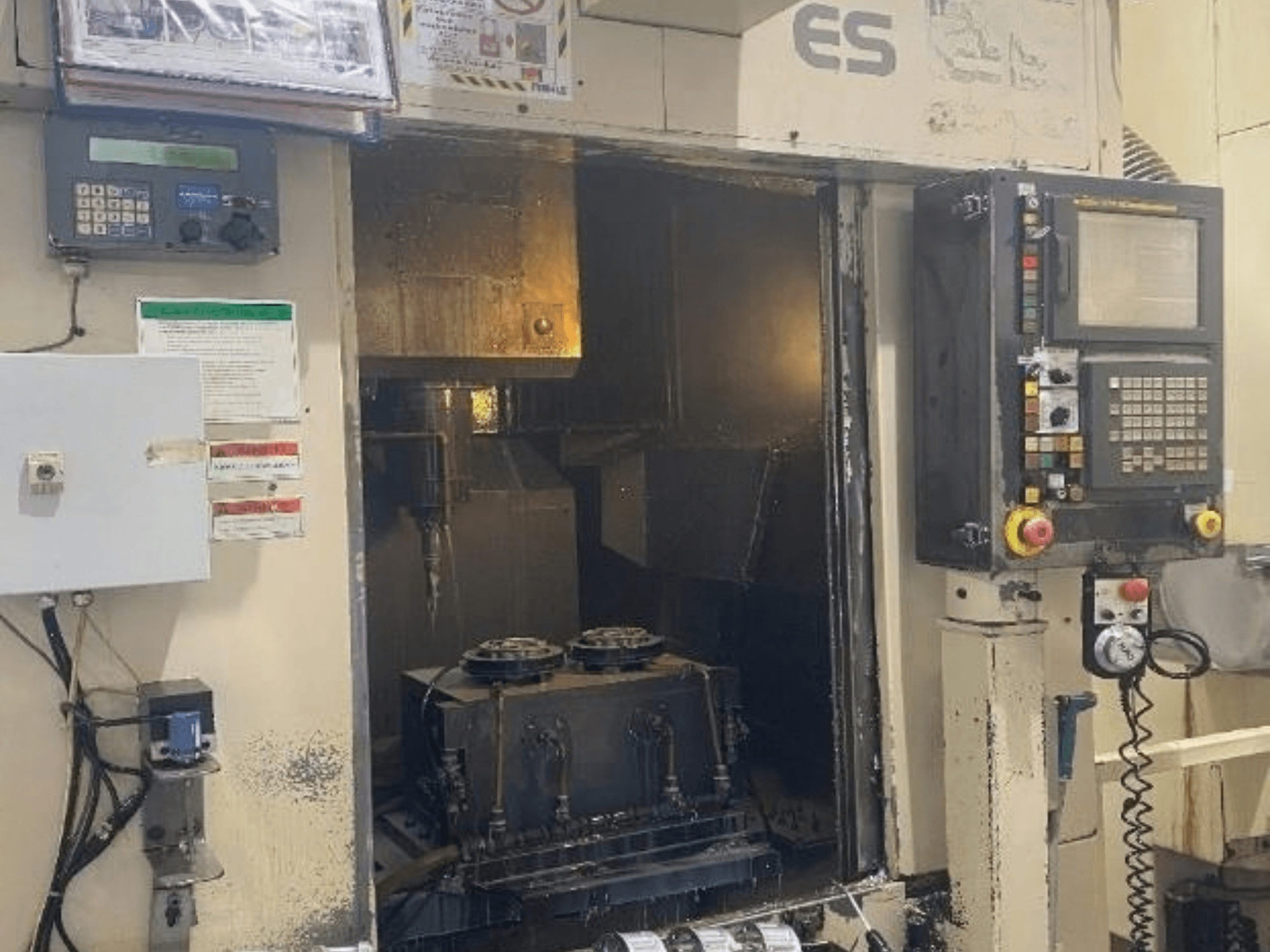 Вид спереди вертикального обрабатывающего центра Enshu ES450 с панелью управления, видом внутренней части и зоной размещения инструментов.