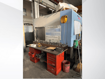 Обрабатывающий центр Doosan с красным верстаком и складом, на котором размещены инструменты и оборудование, вид спереди.