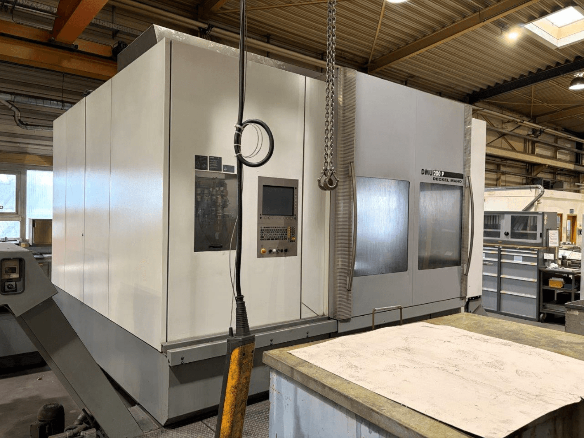 Универсальный обрабатывающий центр DMG MORI DMU 200 в мастерской, вид спереди, демонстрирует панель управления и внешние характеристики.