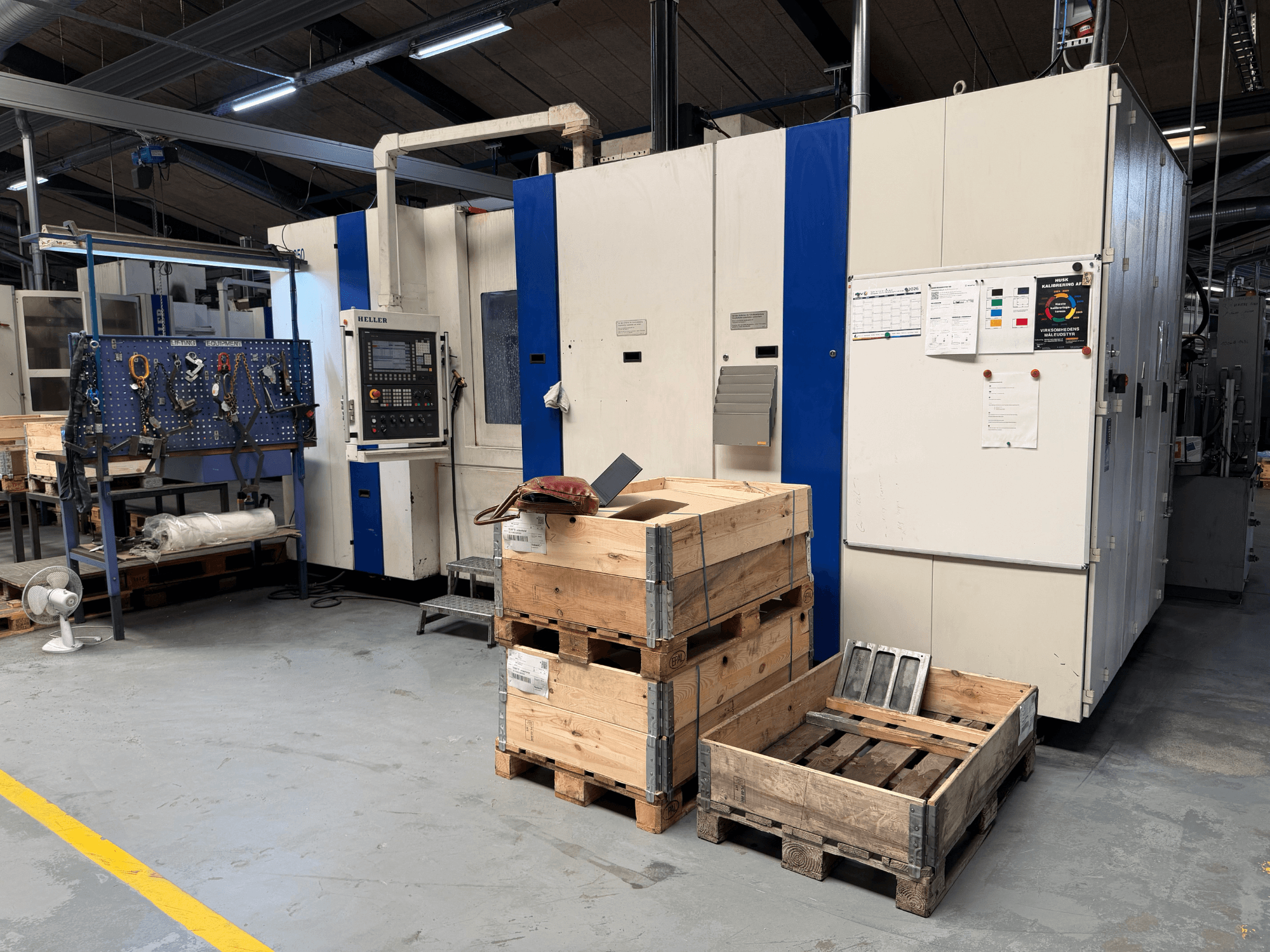 ГОРИЗОНТАЛЬНЫЙ МАШИНОСТРОИТЕЛЬНЫЙ ЦЕНТР HELLER MCH 250 в мастерской, вид сбоку, видны деревянные поддоны и стойка для инструментов.