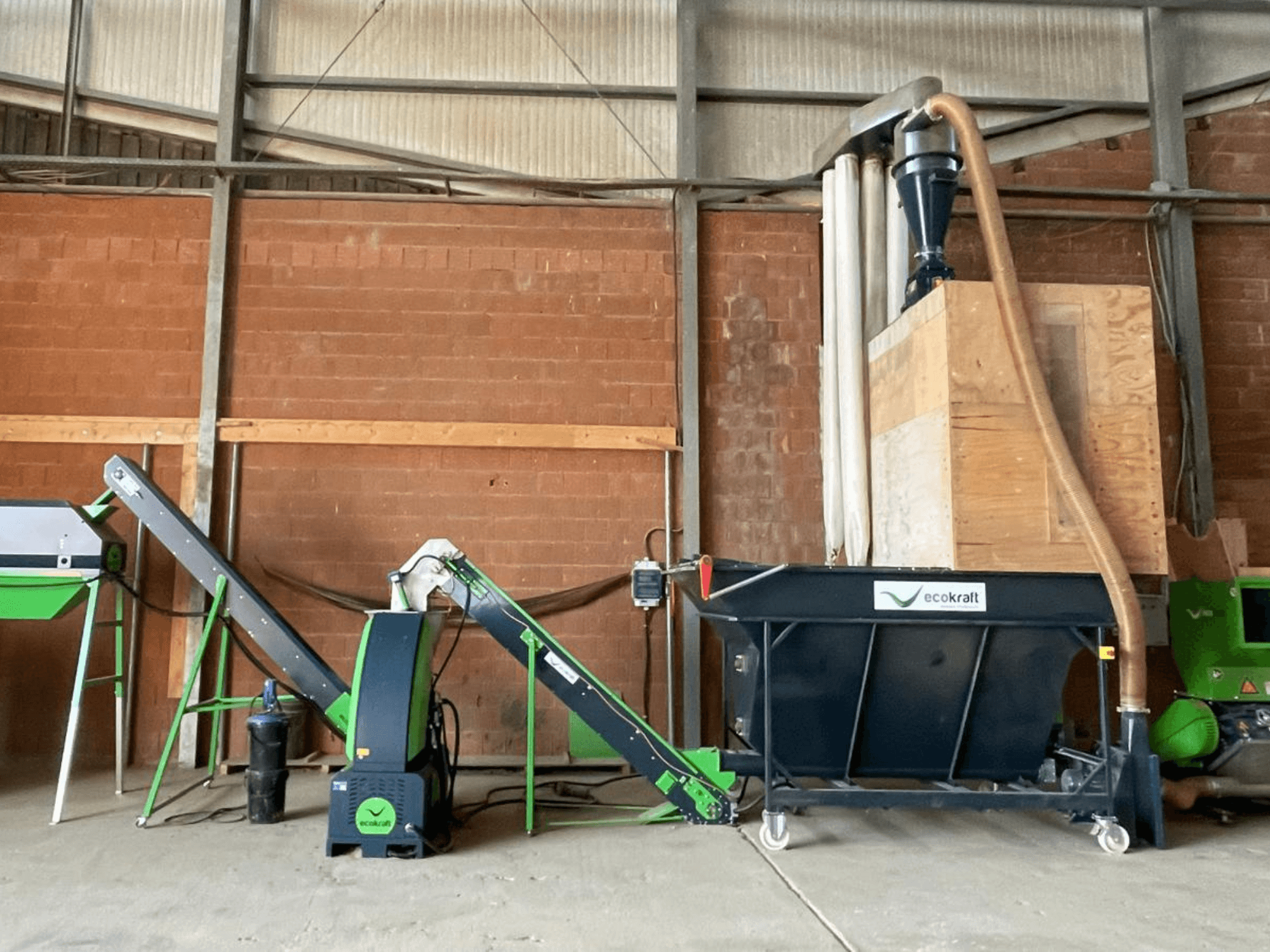 Станк ECOKRAFT LP 22 на складе, оснащенный конвейером и системой пылеудаления. Вид сбоку, на котором видны функциональные узлы.