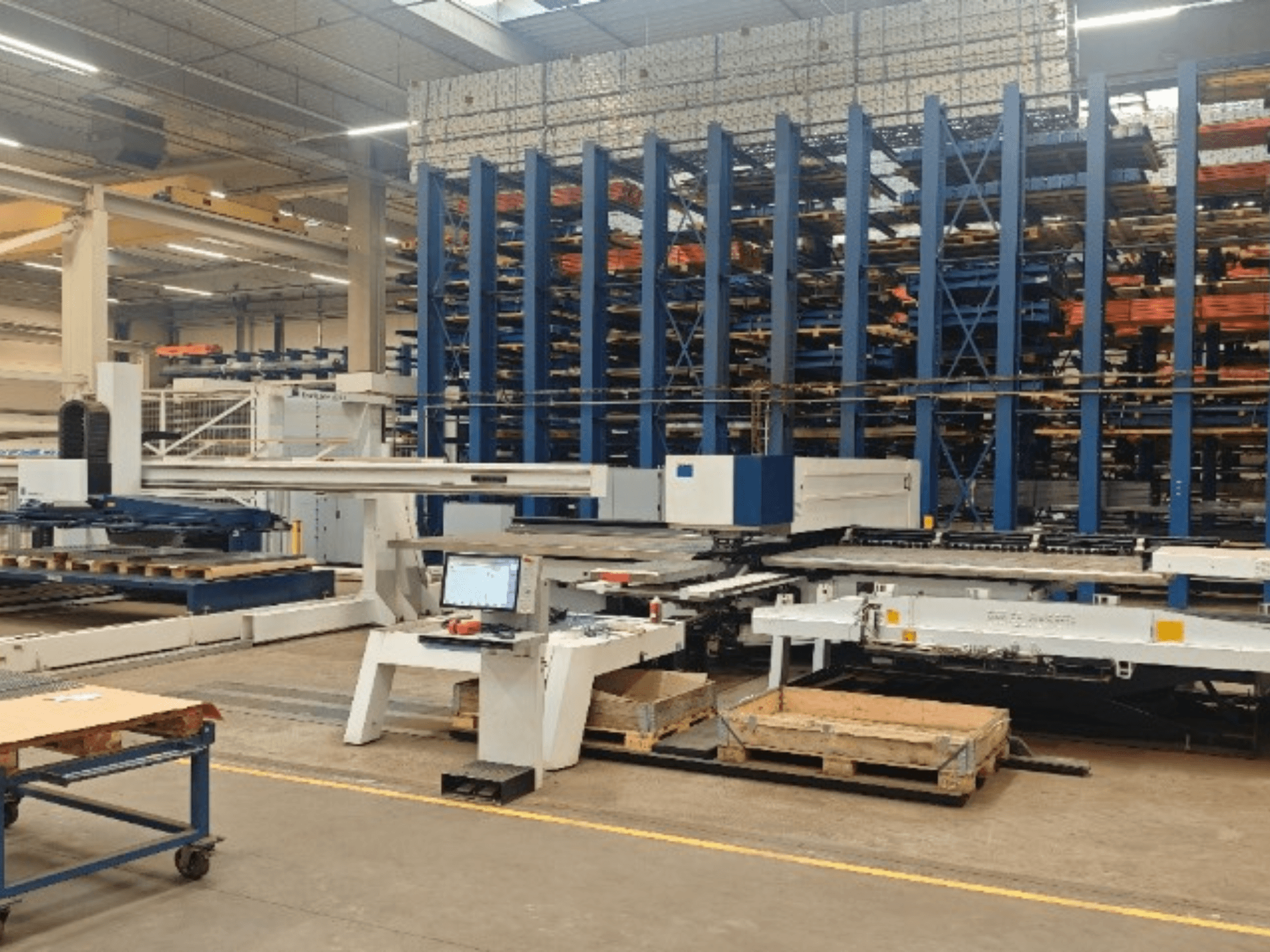 Штамповочный станок с ЧПУ TRUMPF TruPunch 5000 S12 в цехе, вид спереди с панелью управления и зоной хранения.
