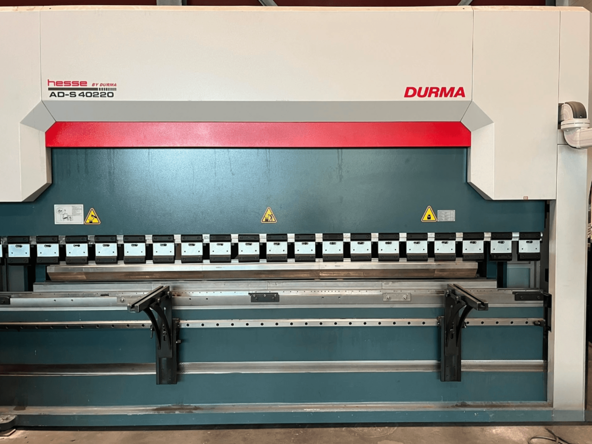 Гибочный пресс Durma AD-S 40220, вид спереди, с несколькими гибочными инструментами и предупреждающими надписями.