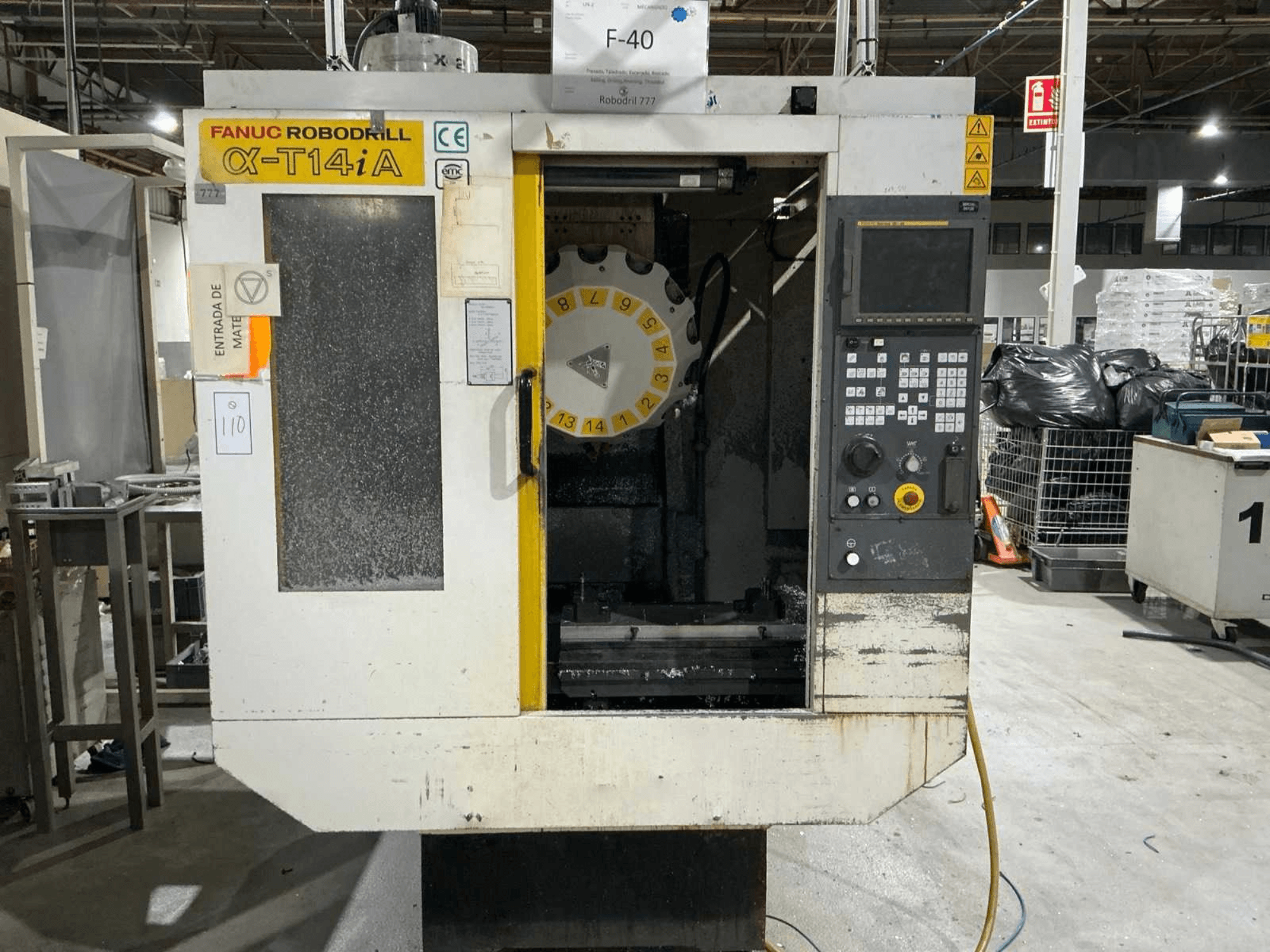 Вертикальный обрабатывающий центр FANUC ROBODRILL α-T14iB, вид спереди с панелью управления и каруселью инструментов.