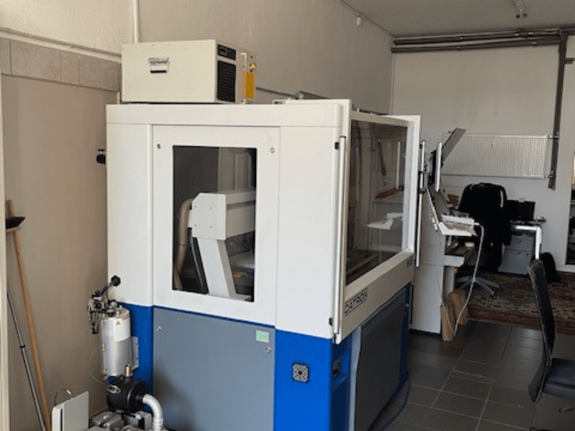 Сине-белая промышленная машина с прозрачными панелями, вид спереди, включает доступ к управлению и видимый вентиляционный блок.