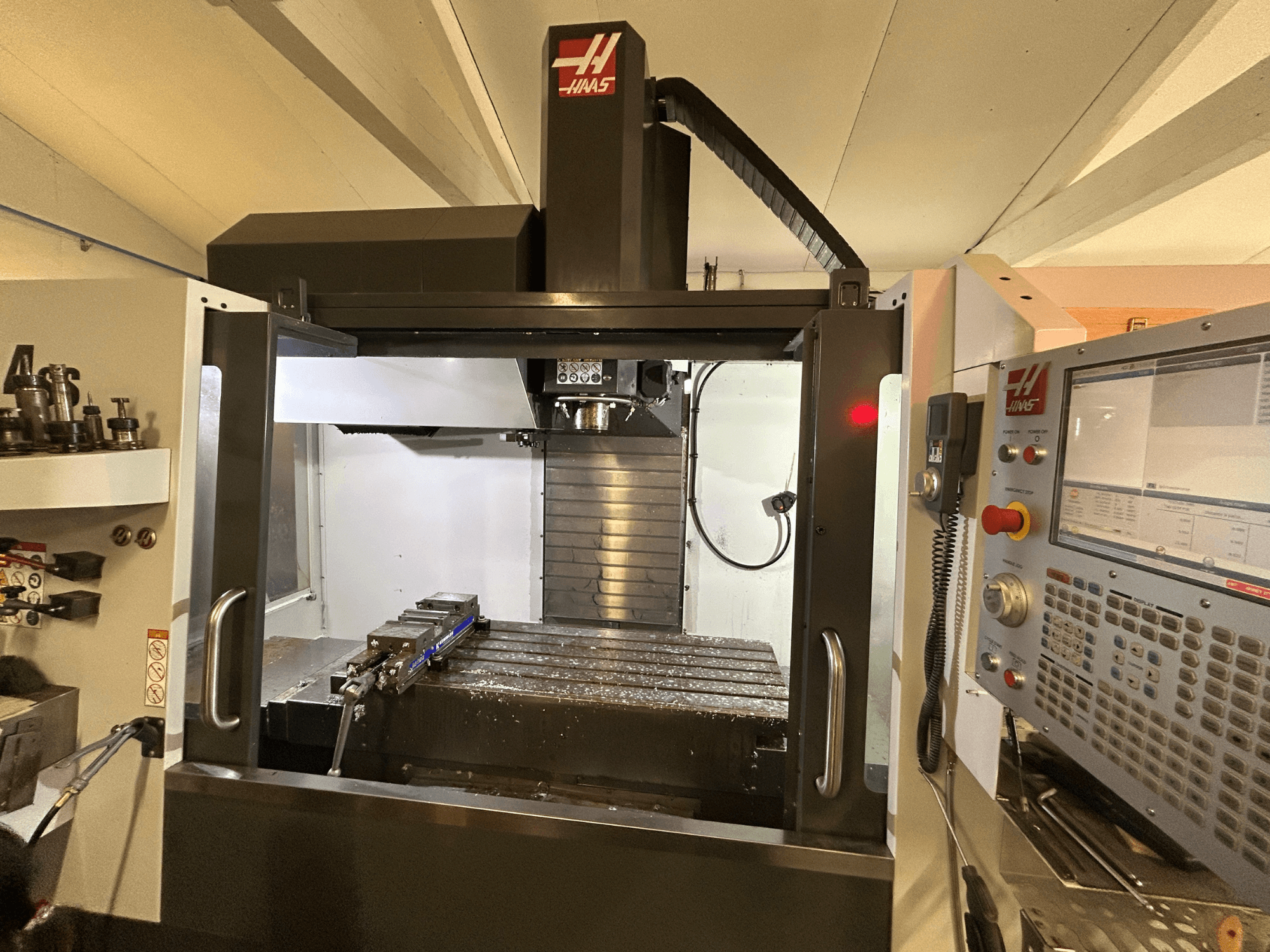 Вертикальный обрабатывающий центр HAAS VF-4SS, вид спереди, демонстрирует панель управления, держатель инструмента и рабочую зону с металлической стружкой.
