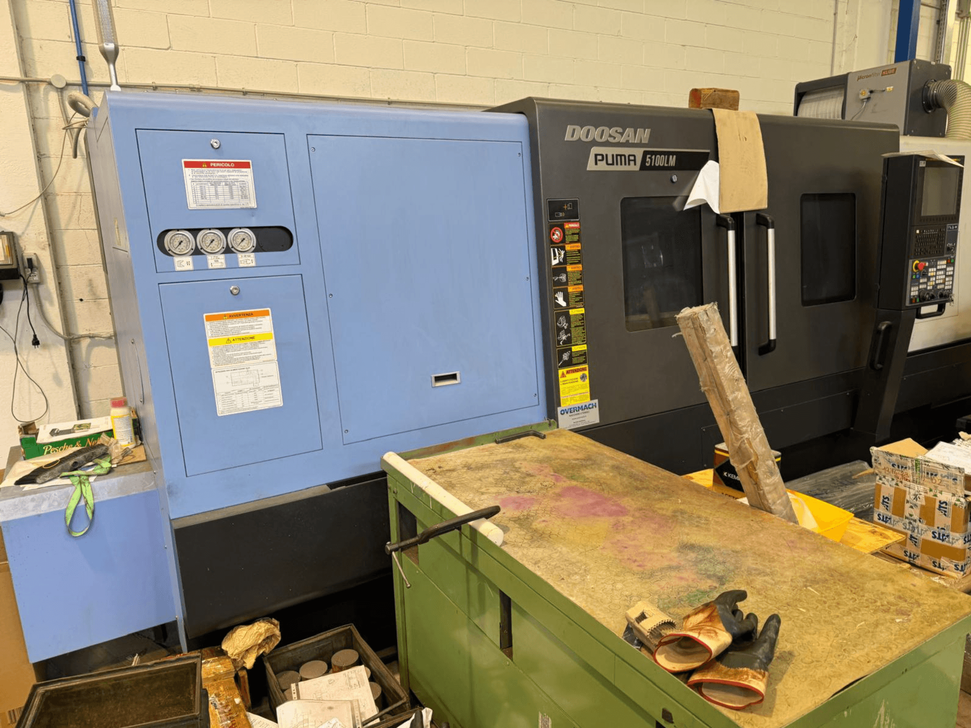 Станок с ЧПУ Doosan Puma 5100LM и панель управления, вид сбоку. На синем блоке управления видны датчики и предупреждающие надписи.