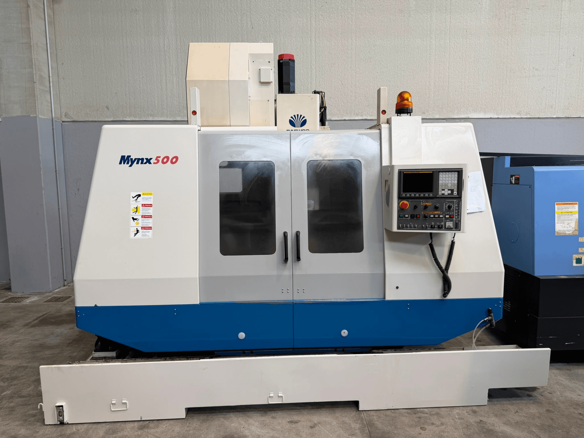 Вертикальный обрабатывающий центр DAEWOO MYNX 500, вид спереди, с панелью управления, сигнальными лампами безопасности и прозрачными дверцами доступа.