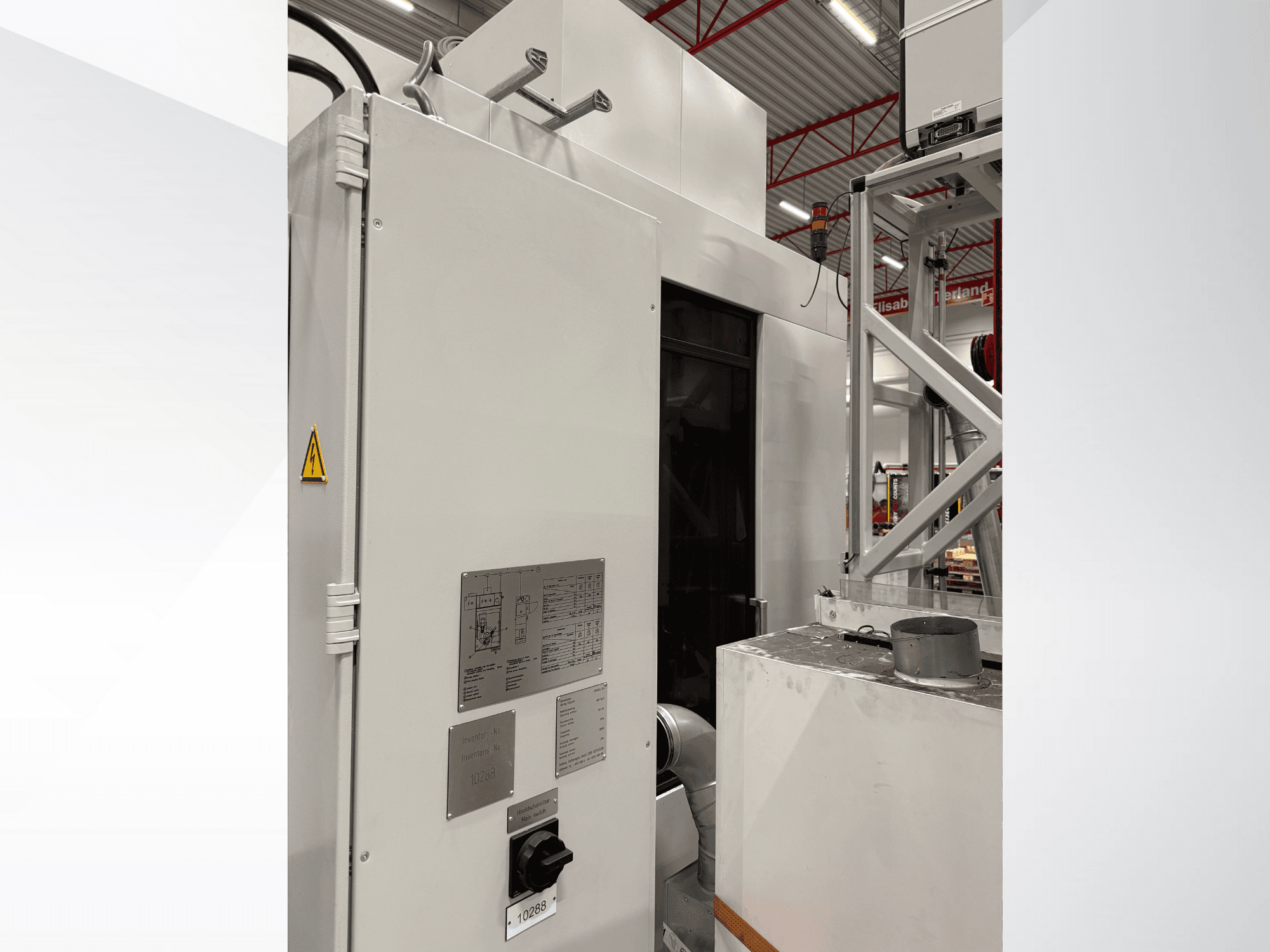 Вид сбоку на белую промышленную машину с панелью управления и предупреждающей надписью, часть автоматизированной системы.