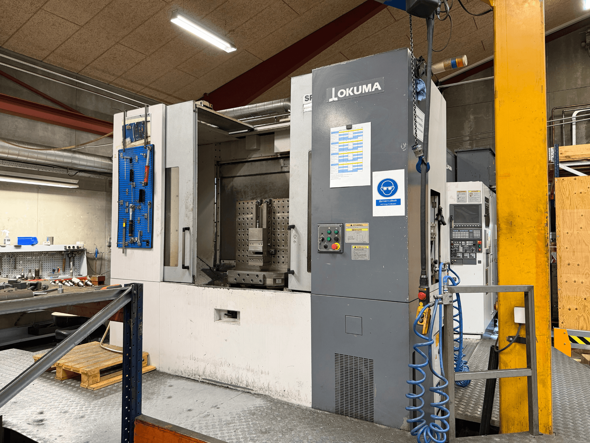 Горизонтальный обрабатывающий центр Okuma MA-600HB в цехе, вид спереди с панелью управления и рабочей зоной.
