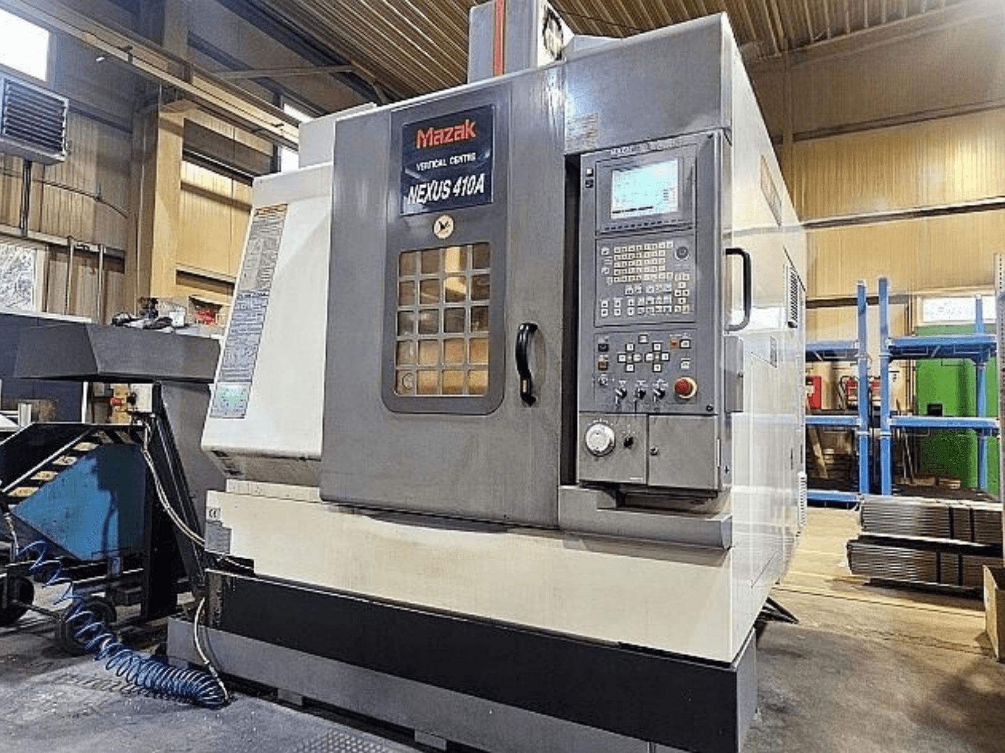 Вертикальный обрабатывающий центр Mazak VCN-410A, вид сбоку, на котором видны панель управления, держатель инструмента и рабочие элементы.