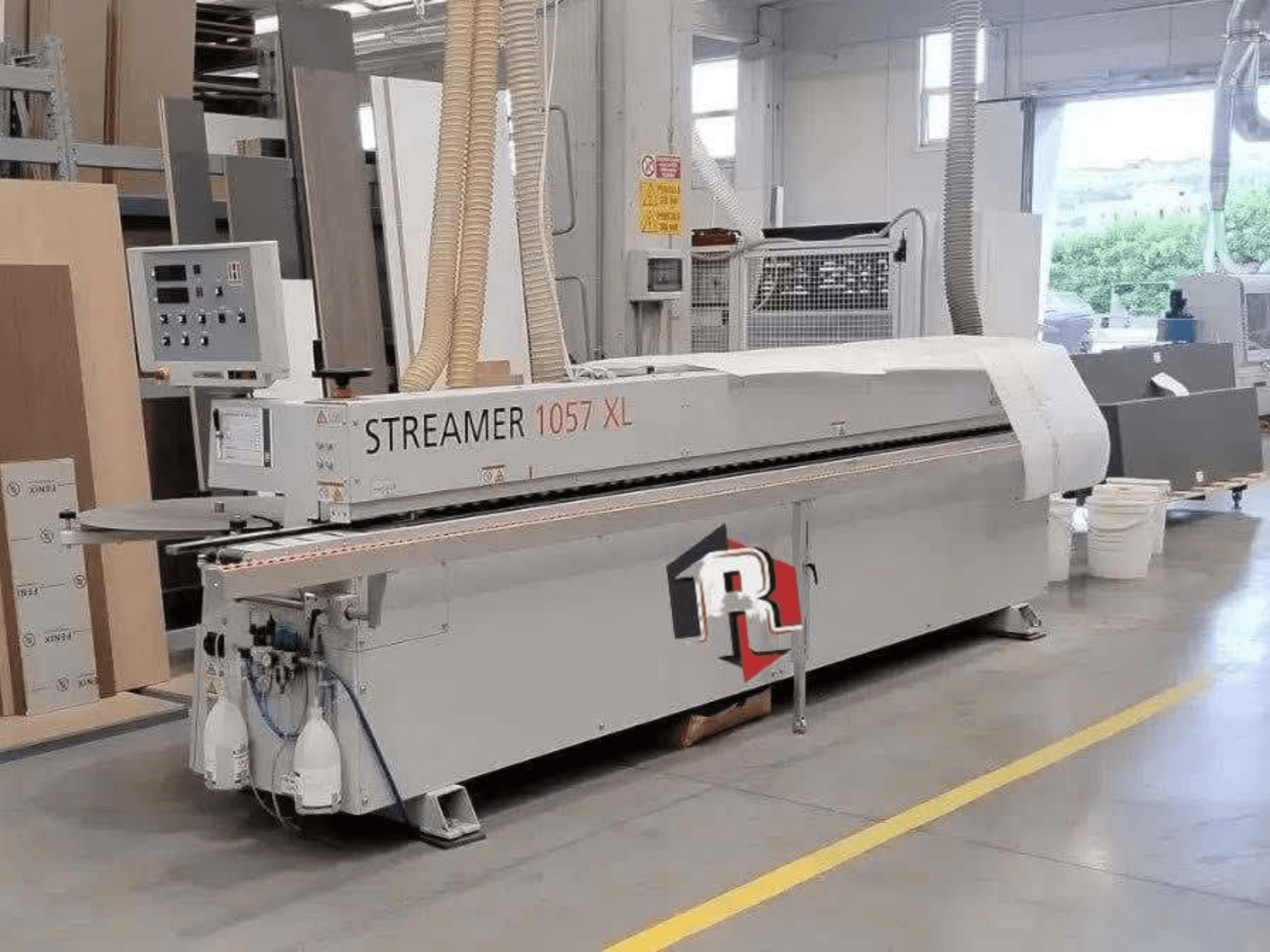 Кромкооблицовочная машина HOLZHER STREAMER 1057 XL в цехе, вид сбоку с видимой панелью управления и пневмошлангами.