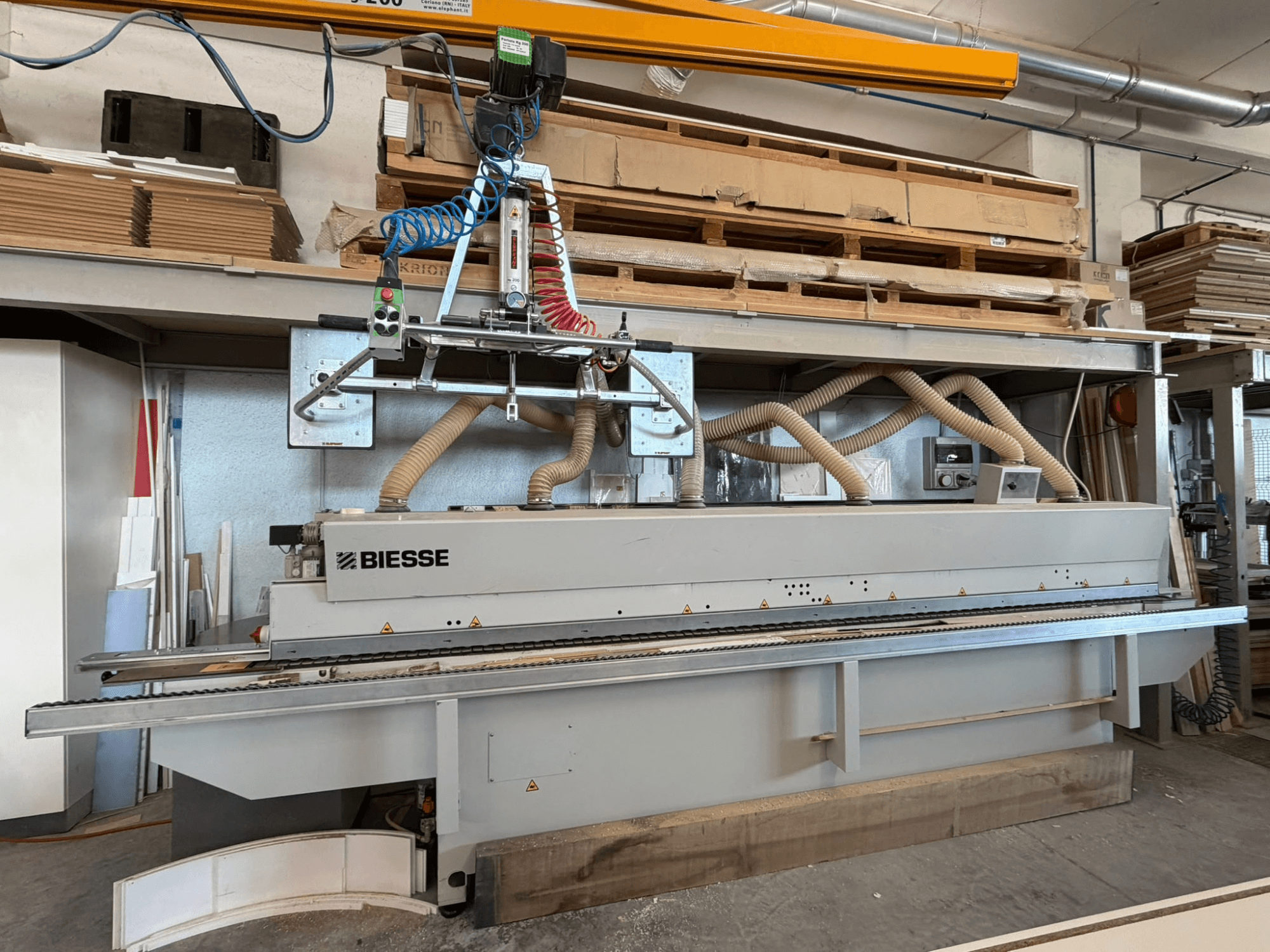 Кромкооблицовочная машина BIESSE AKRON 1330 в цехе: вид спереди с панелью управления и системой пылеудаления.